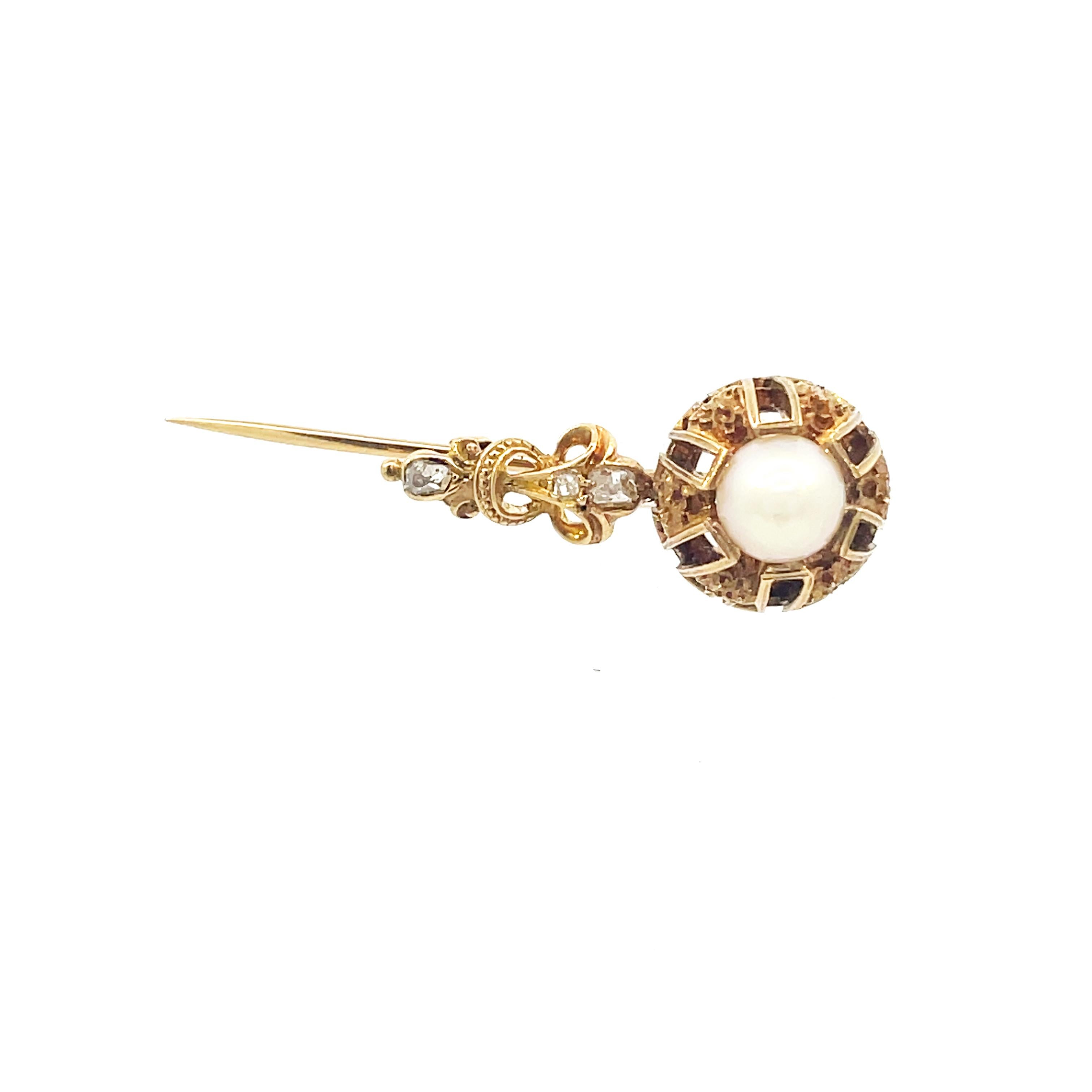 This is an outstanding Victorian pin, crafted in 14K yellow gold, and features a beautiful collection of old mine cut diamonds and a lovely natural pearl. This elegant pin is adorned with beautifully engraved details along the body of the pin, with