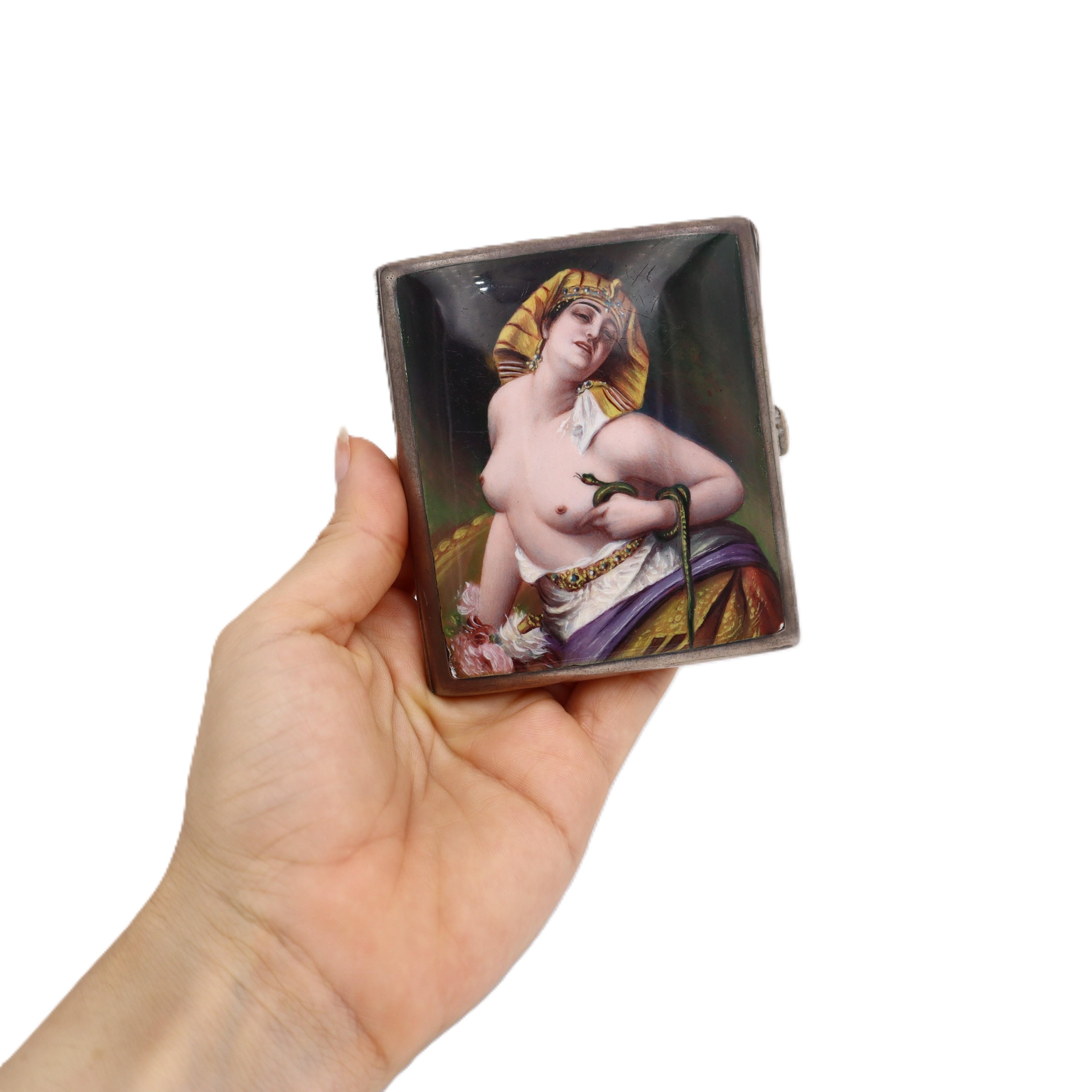 This stunning antique cigarette case represents the pinnacle of Victorian-era craftsmanship, expertly crafted from solid sterling silver and featuring an impressive enamel image of Cleopatra, the iconic queen of Egypt, elegantly holding a snake.