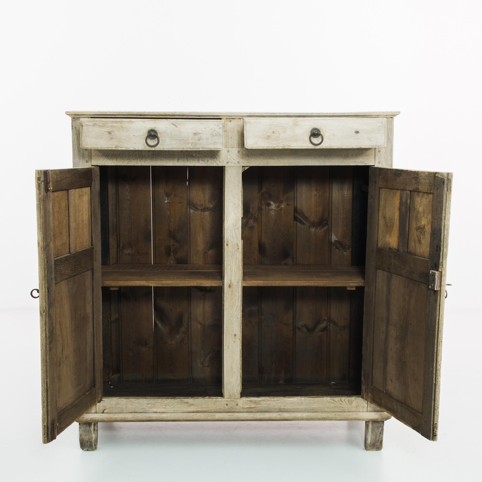 An oak buffet from 1860s Belgium. An upright frame, elevated upon square feet; panelling on the cupboard doors and cabinet adds a sober decorative touch. Door hinges, lock pieces and drawer handles in cast-iron lend a subtly gothic inflection,