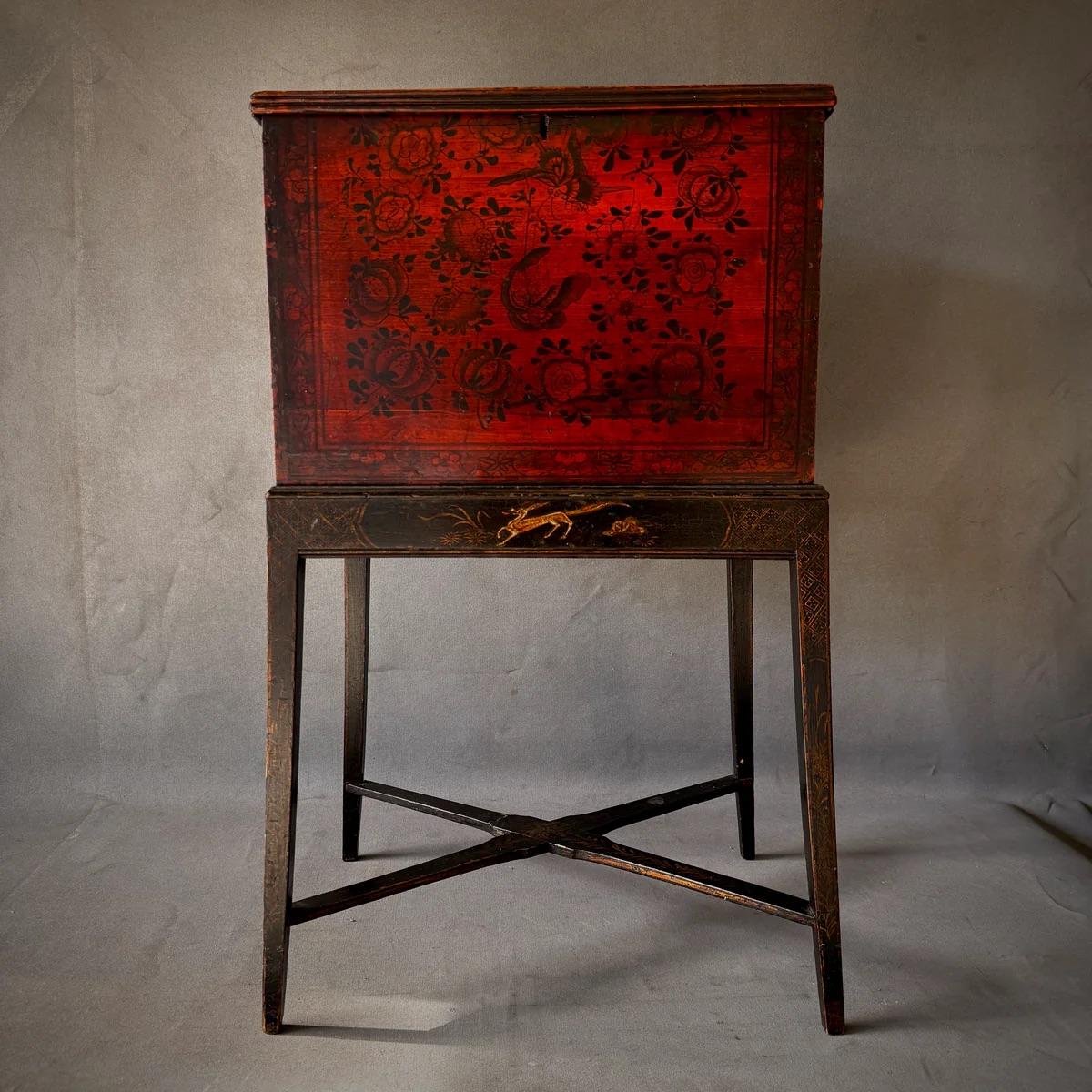 Scatola da tè della fine del XIX secolo importata dalla Cina. Decorata con una splendida flora e fauna dipinta a mano in rosso e nero e dotata di maniglie rettangolari in ferro, la scatola è montata su una base in legno ebanizzato con decorazioni