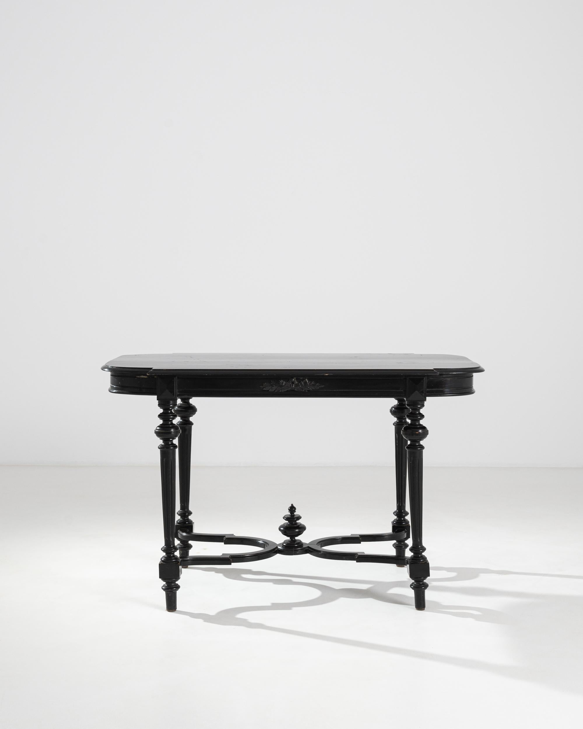 A black painted wooden table from 1860s France. Neatly lathed legs and accents, paired with a subtly patinated coat of black paint combine to create a refined side table. A leaf pattern carved into the table’s apron boasts craftsmanship and care.