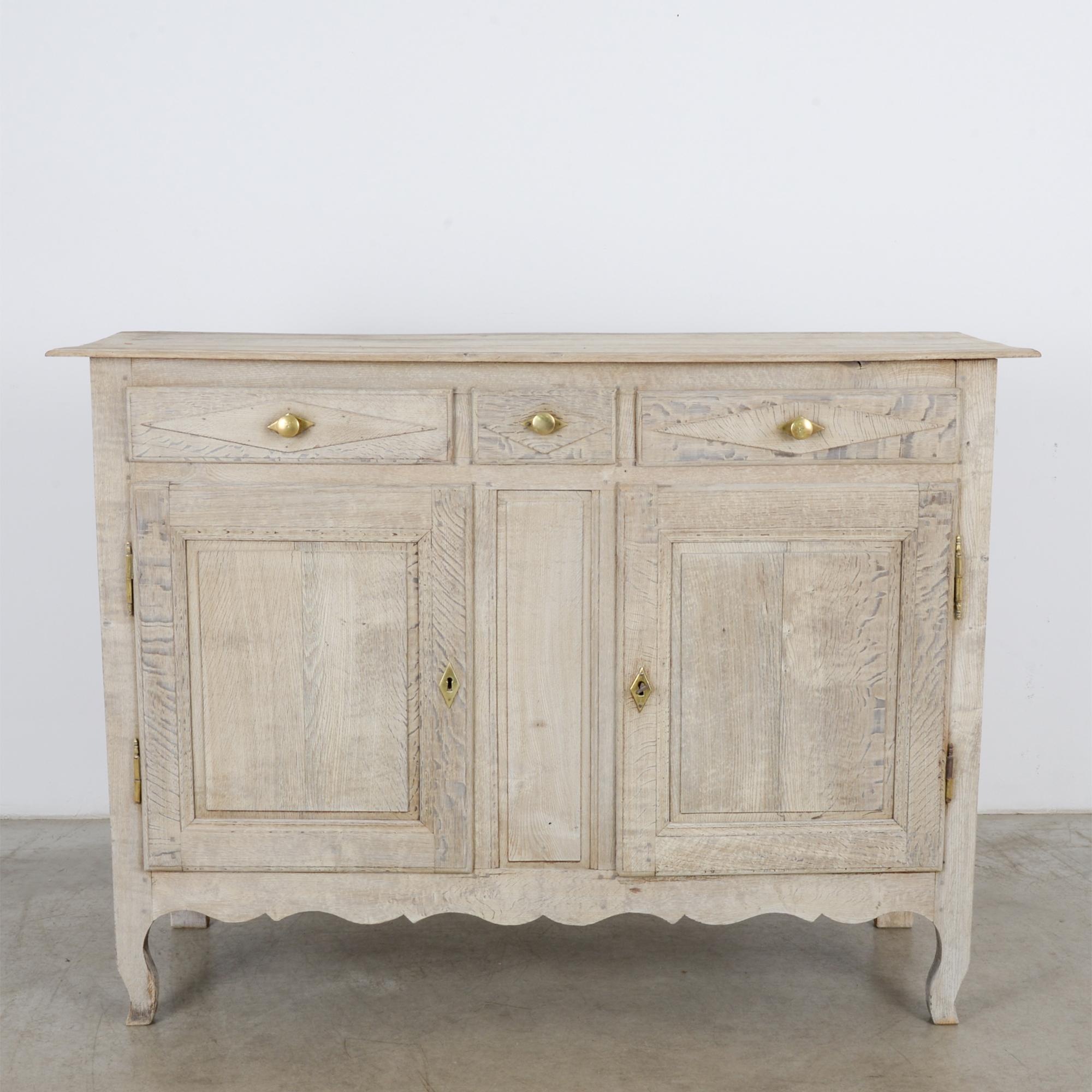 A 19th century French oak buffet cabinet. This vintage buffet has plenty of room with two doors and three drawers featuring casted bronze knobs for a clean finish that accentuates the grain of the bleached oak. A beautiful sturdy piece that’ll add a
