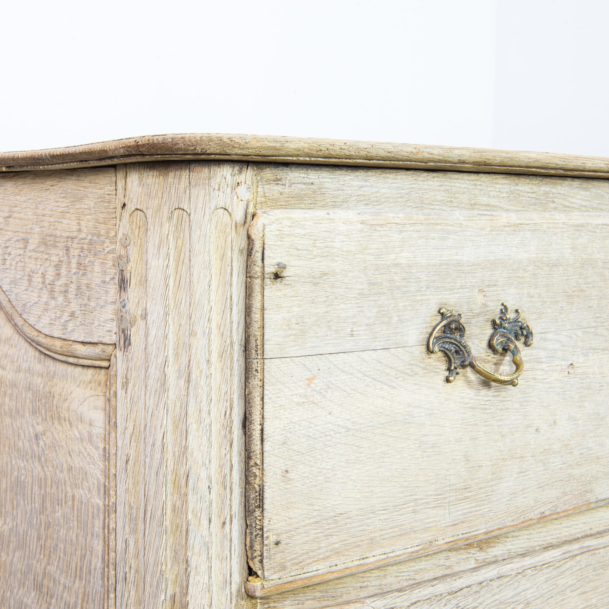 Made in France, circa 1860, this bleached oak chest of drawers enchants with its intricacies and fine workmanship. The reeded corners, decorative pulls, and elaborately carved apron of scallop shells and foliage express the beauty of the French