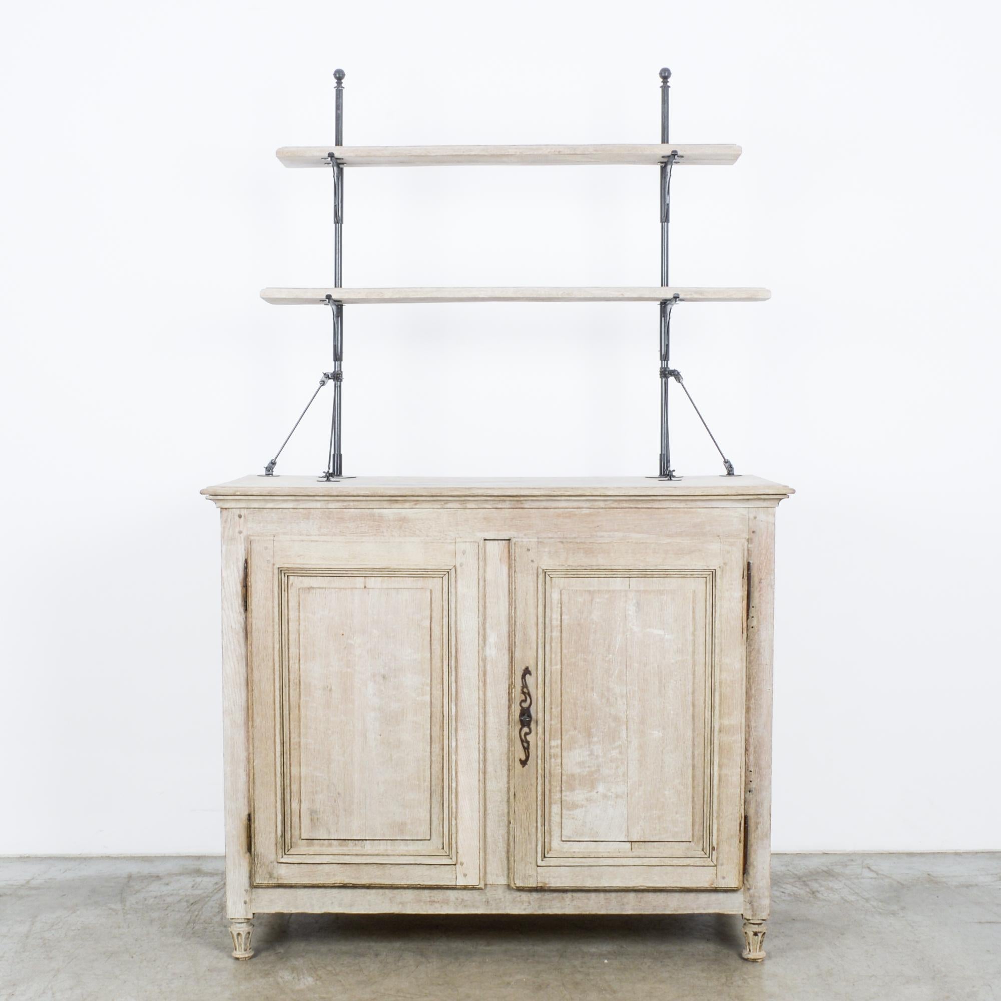 This bleached oak cabinet was made in France, circa 1860. The display portion is refurnished with metallic shelving supports and decorative brackets, creating a piece that blends a rustic farmhouse charm with an Industrial edge. The credenza below