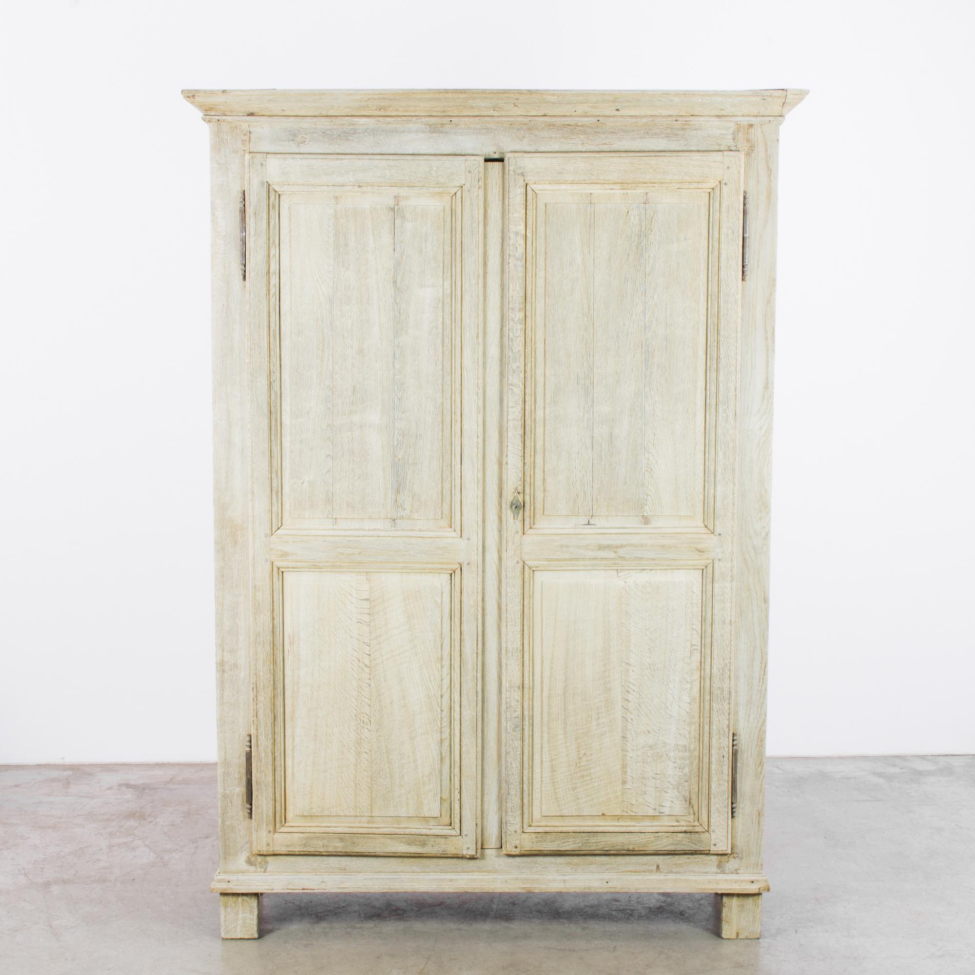 An oak armoire from 1860s, France. The oak has been restored to a bright, luminous finish, lending a lightness and agility to the broad silhouette. Paneled doors open onto the sable-colored wood of the interior, gently iridescent. Three shelves