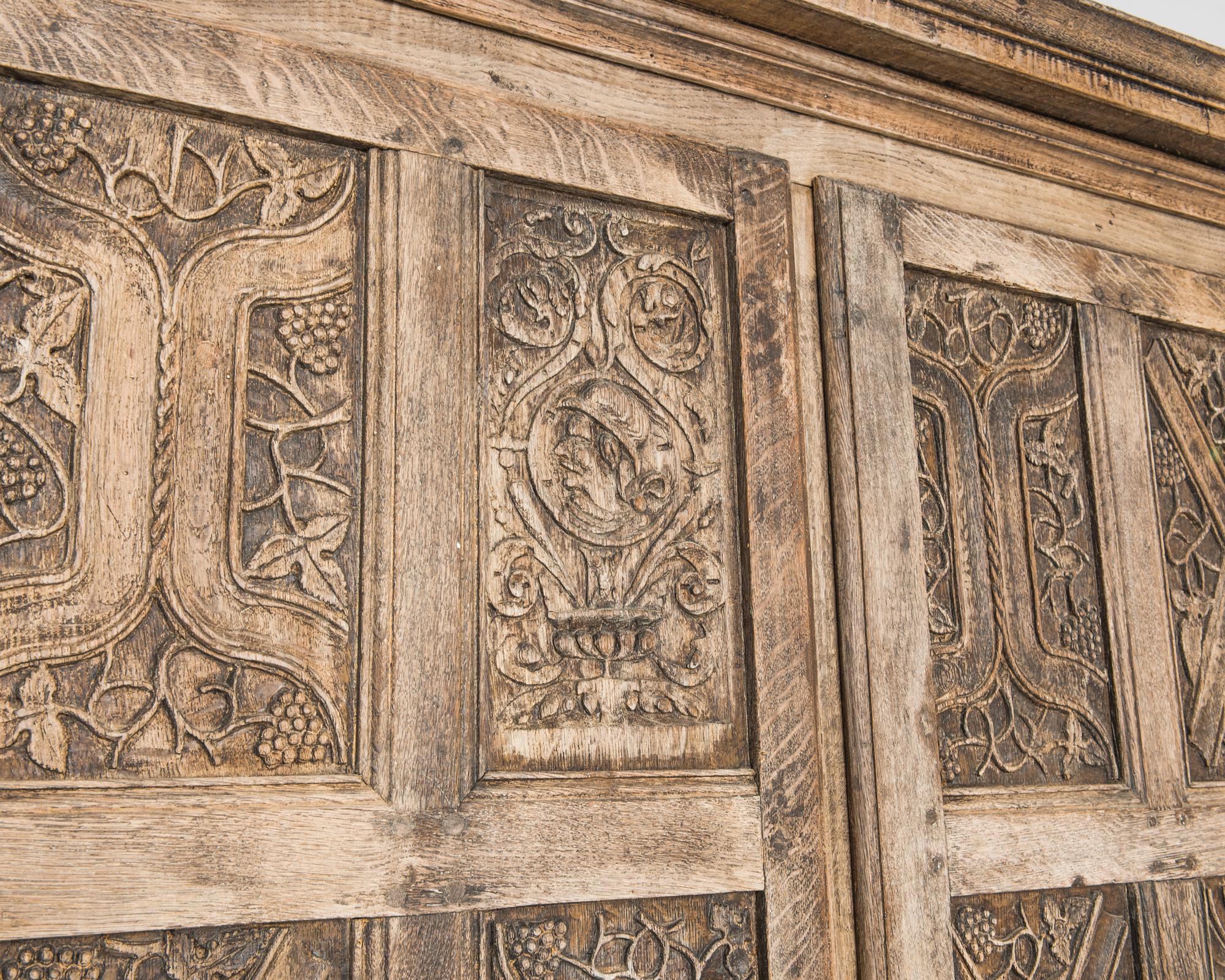 The intricacy of the carved panelling gives this oak cabinet the impression of an illuminated manuscript. Made in France in the 1860s, the double doors are divided into sixteen panels, each with a verdant design of brackets and vines. Carved grapes