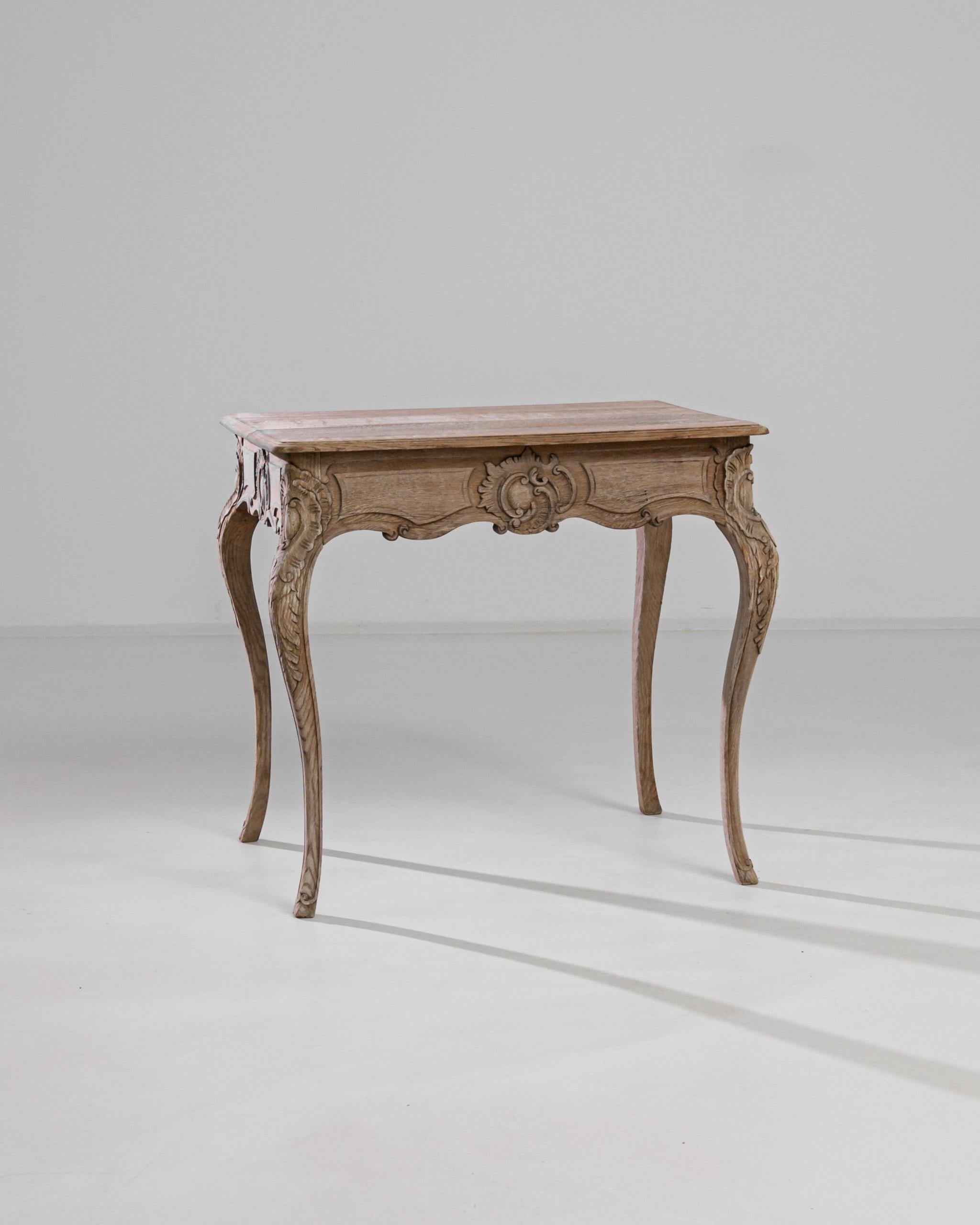An antique bleached oak table from France with distinctive curved legs. Stylish and practical with a versatile shape, four limbs stretch to support the scalloped apron and a softly beveled tabletop. 

Perched on cabriole legs – the piece imparts a