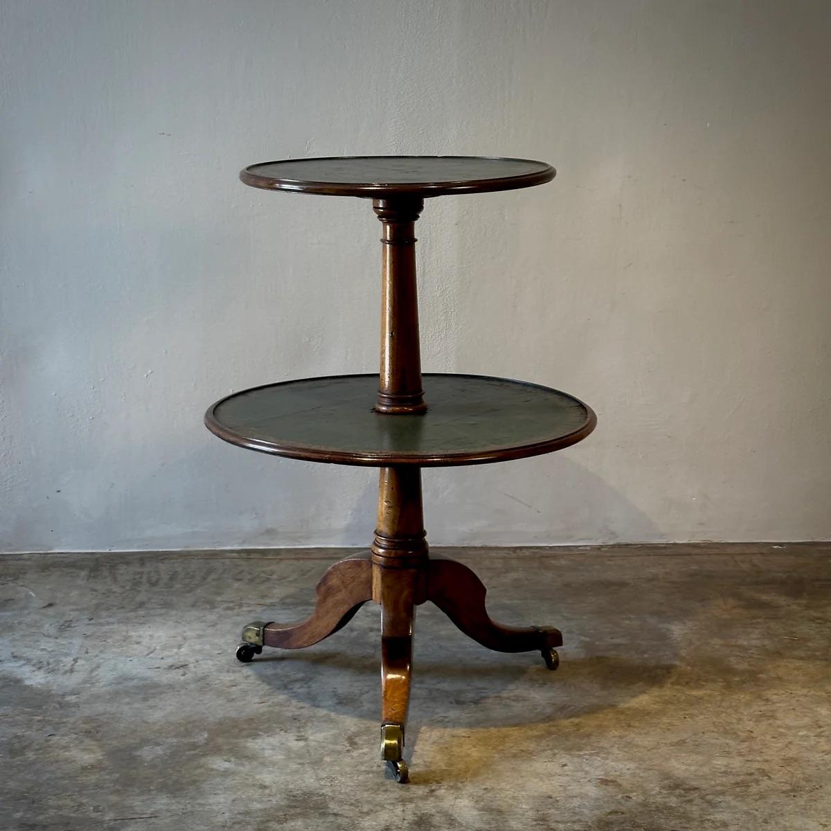 Cette table circulaire est un mélange d'élégance et de praticité avec son design à deux niveaux et son exquis plateau en cuir bleu foncé, agrémenté d'une bordure dorée et ornée de motifs floraux. La table repose sur un piètement tripode en balustre