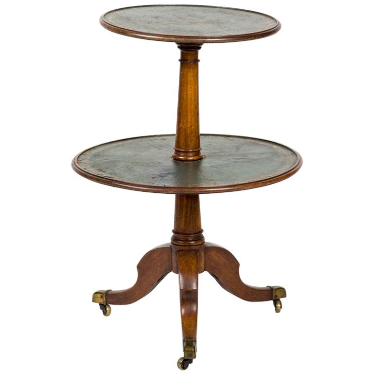 Circular two-tiered table from mid 19th-century France with a dark blue leather top. The top is handsomely finished with a tooled gilt border in a floriated motif. The carved baluster tripod base is mounted on casters. A classic piece with great