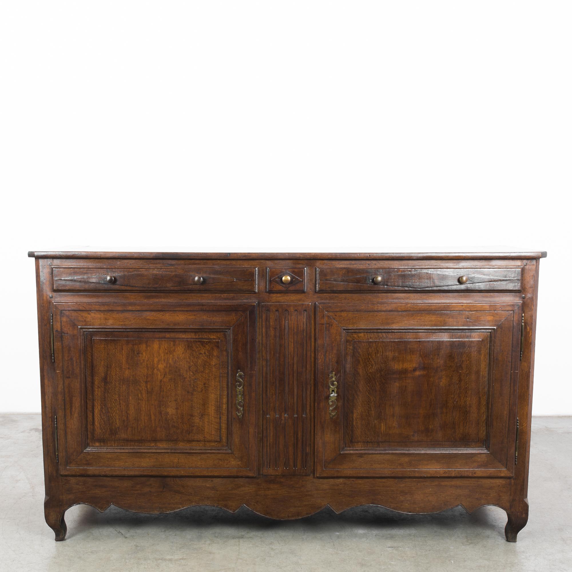 A wooden buffet from 1860s, France. A broad, low-set shape gently elevated on cabriole legs with a graceful contoured apron. The wood is a deep chocolate color, with a rich polish. Diamond accents on the drawers provide a stylish geometric note.