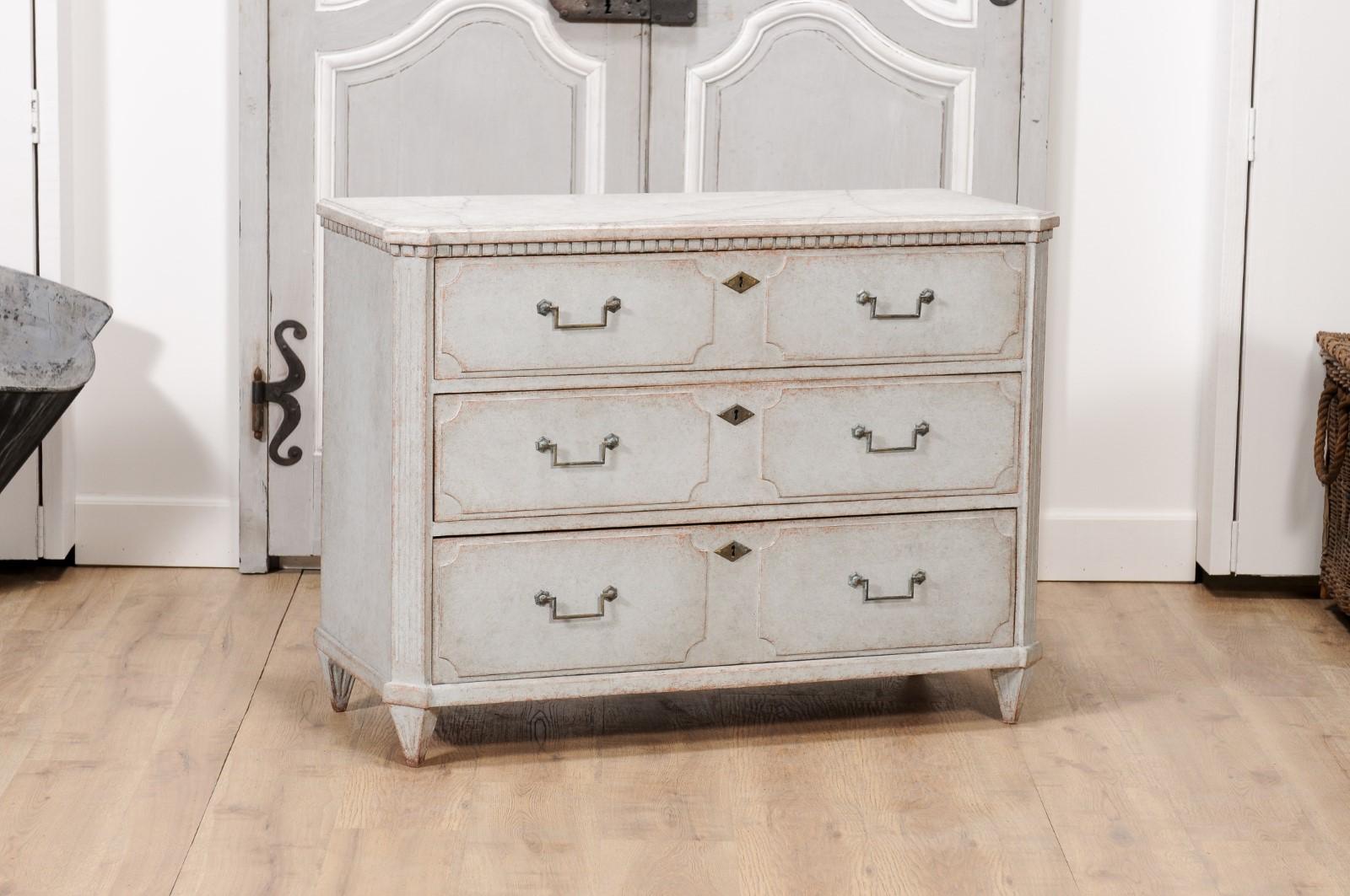 A Swedish Gustavian style painted wood chest from circa 1860 with marbleized top, carved dentil molding, three drawers, low-relief cartouches, fluted side posts and short tapered feet. This Swedish Gustavian style painted wood chest from circa 1860,