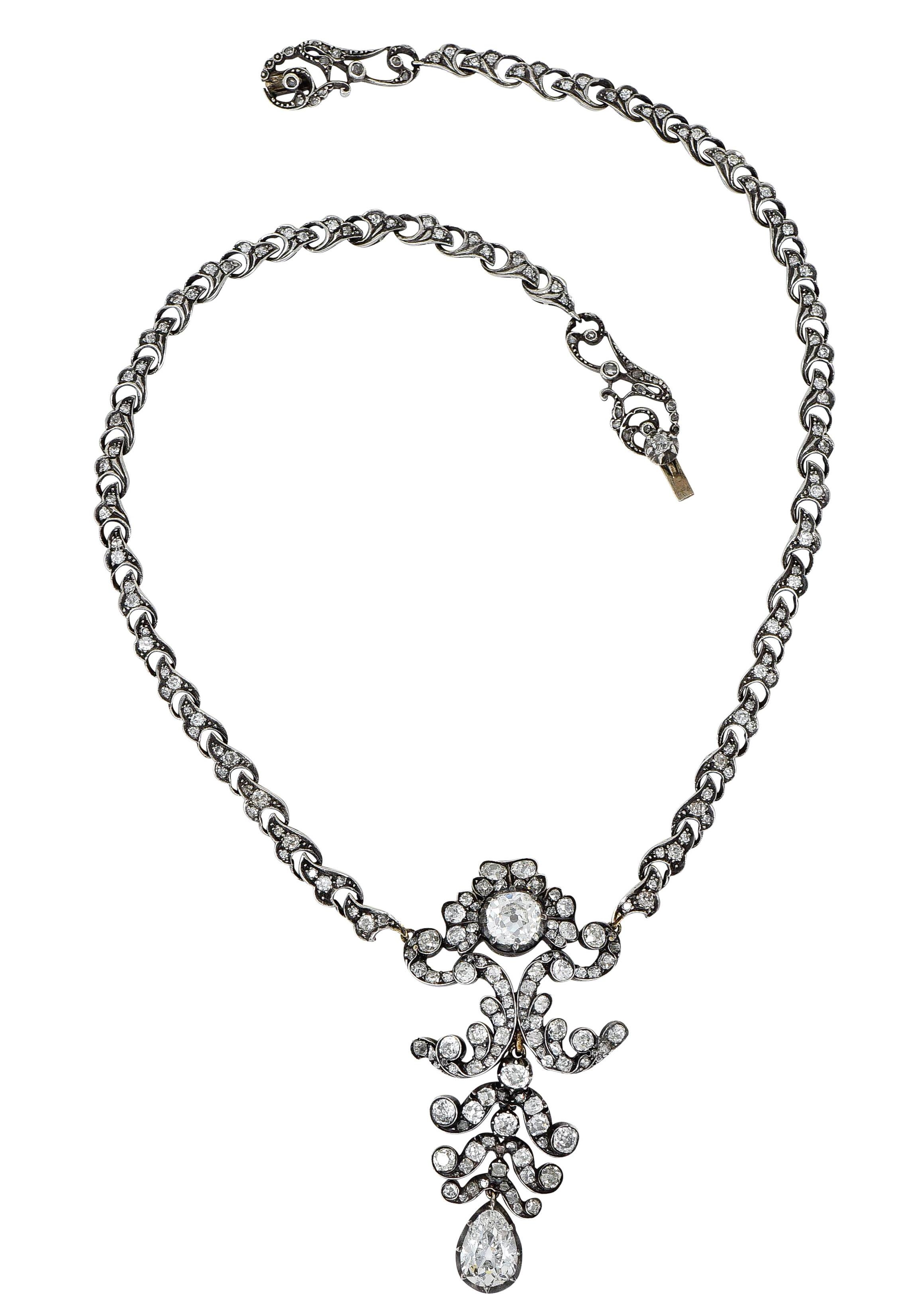 Necklace is comprised of stylized ginkgo leaves that center an ornate floral station

Featuring a large old mine cut diamond weighing 1.73 carats - I color with SI1 clarity

And suspends an articulated drop featuring a pear cut diamond weighing 2.38