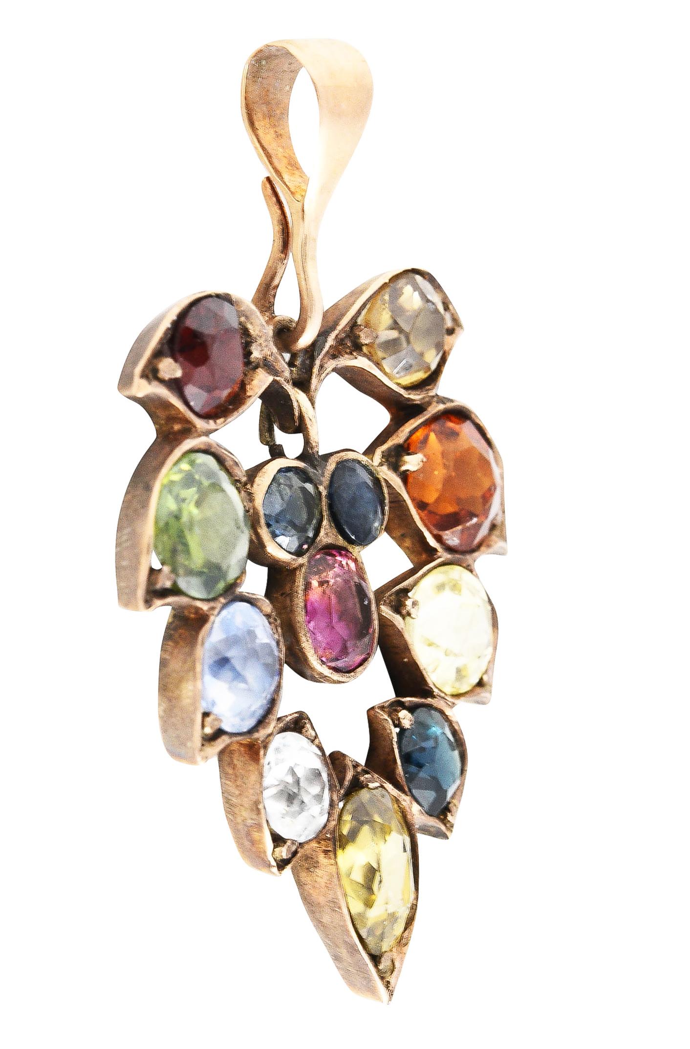 Pendant is designed as a flourishing leaf motif with an open center that suspends an articulated drop. Set throughout by a zircon, garnets, and fancy colored sapphires. Sapphires weigh collectively approximately 6.00 carats. Completed by a removable