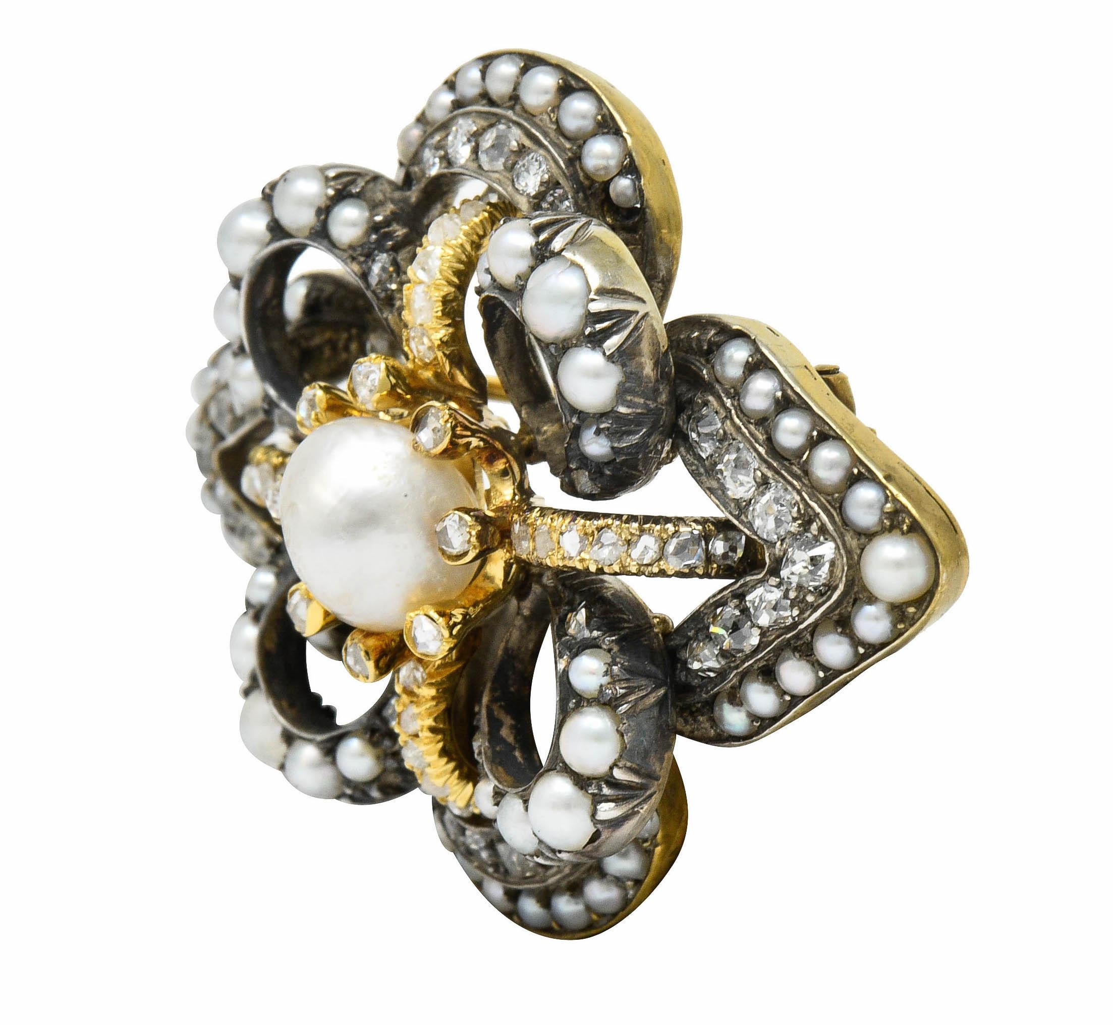 Brooch features two overlapping stylized and dynamic quatrefoil forms creating a floral design

Centering a 7.8 mm semi-round baroque pearl with white body color and features strong rosè overtones; good in luster

Surrounded by natural freshwater