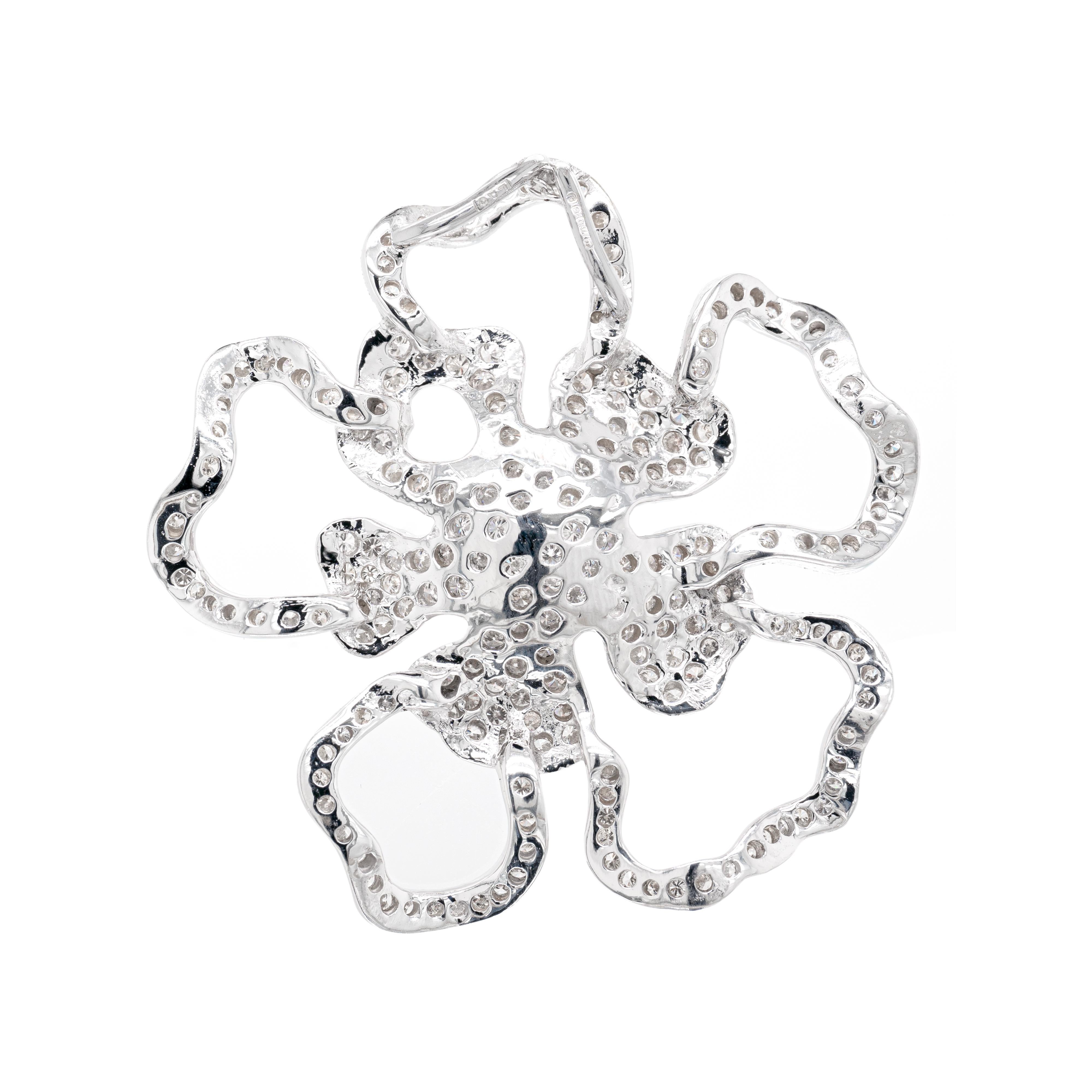 This stunning 18 carat white gold pendant is beautifully design as an open work flower, whose petals are meticulously inlaid with fine quality round brilliant cut diamonds. The flower's outer petals are made just as an outline, while the inner ones