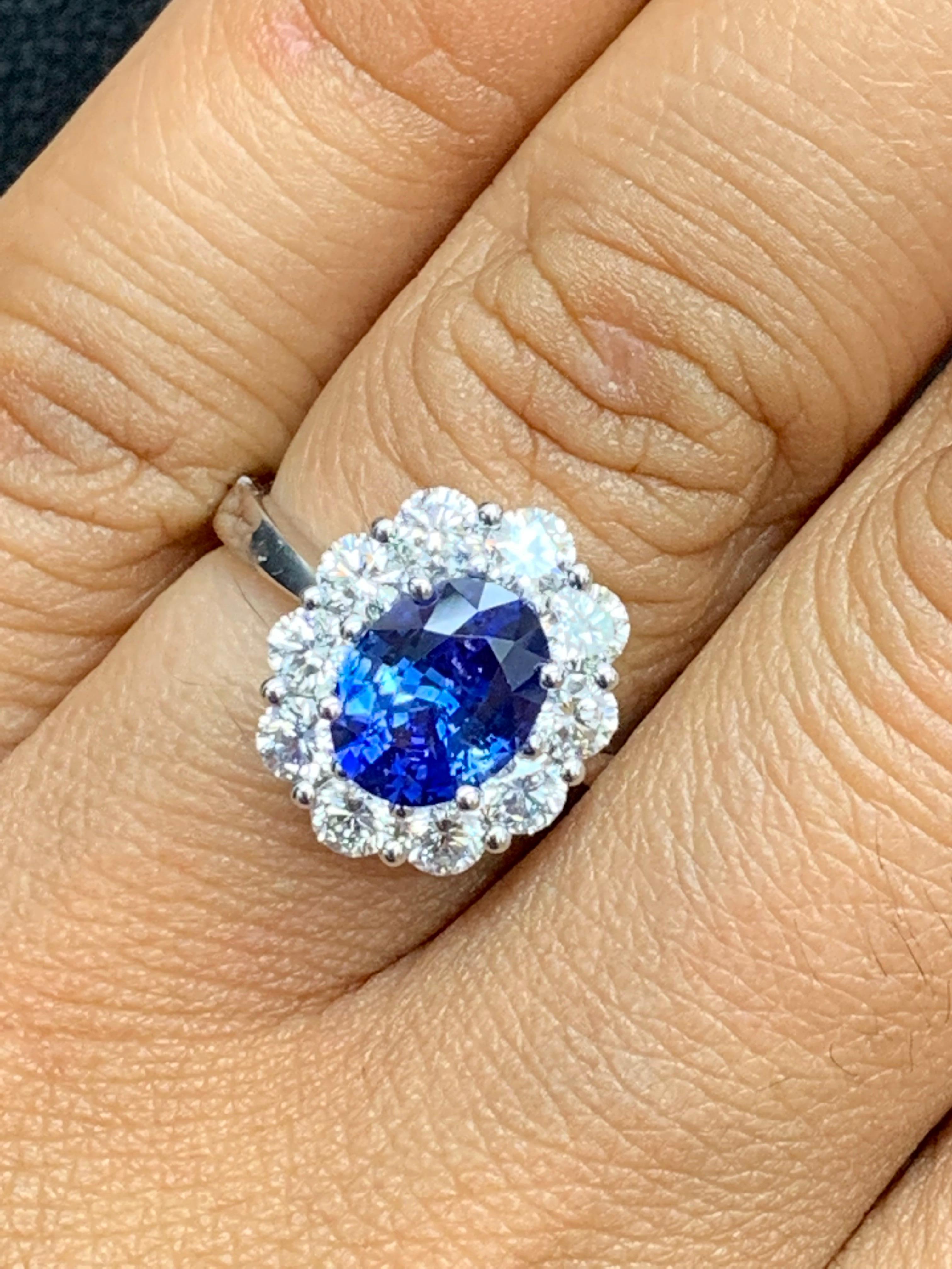 Showcasing a color-rich oval cut blue sapphire weighing 1.87 carats, surrounded by a single row of brilliant-cut diamonds set in a flower design halo. 10 Diamonds weigh 
1.17 carats total. Made 18k white gold 

Style available in different price