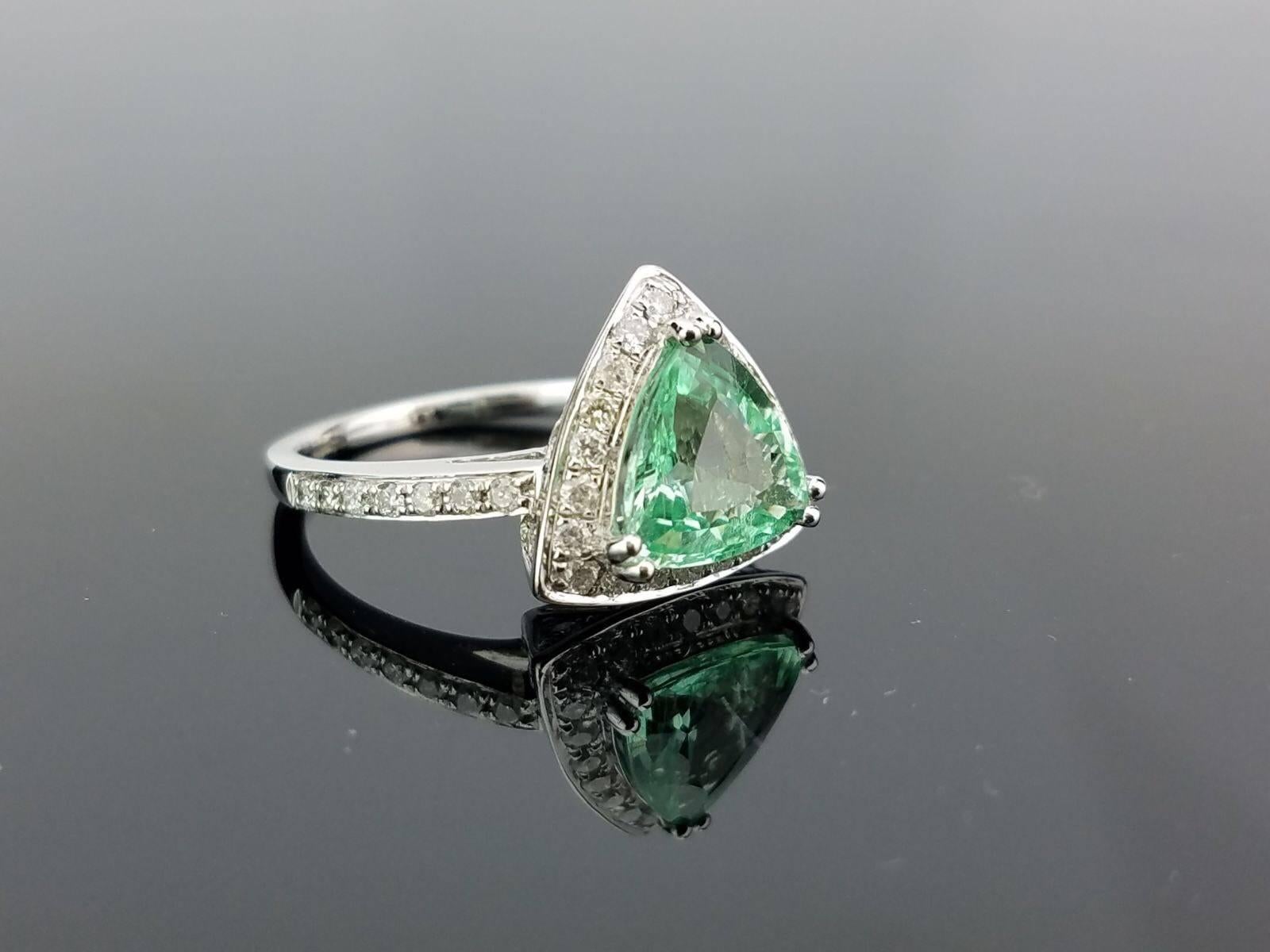 An elegant ring using a beautiful blue-green coloured, rare, trillion shaped Pariaba, surrounded with White Diamond, all set in 18K white gold. 

Stone Details: 
Stone: Pariaba
Carat Weight:  1.87Carats

Diamond Details: 
Total Carat Weight: 0.6