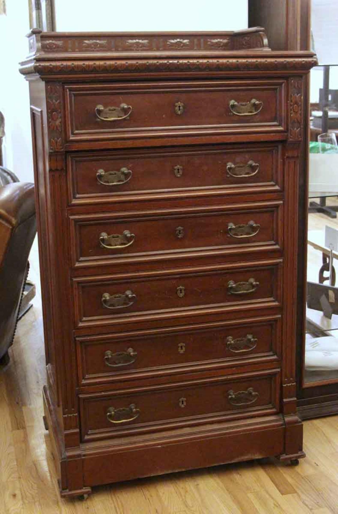 1870s dark tone six-drawer antique mahogany tall boy dresser with decorative carved details. Top drawer has six adjustable compartments. Small crack in one drawer on bottom. Key works on every drawer but the 2nd. This can be seen at our 333 West