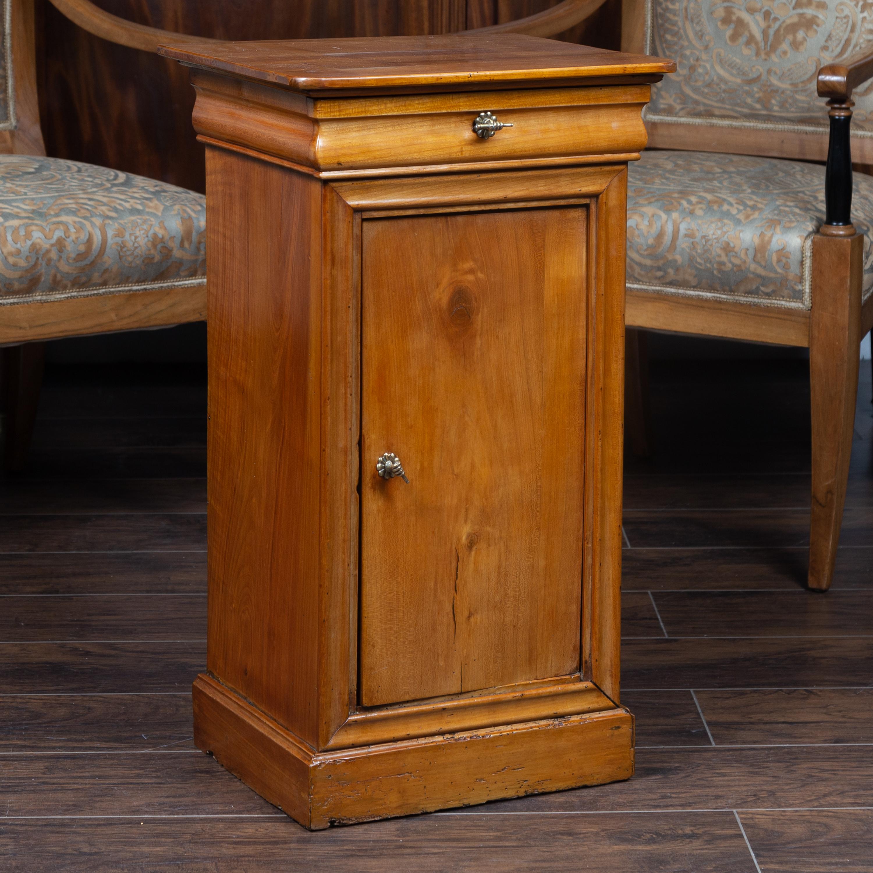 An Austrian Biedermeier style walnut bedside cabinet from the late 19th century, with single drawer, door and brass hand pulls. Born in Austria during the second half of the 19th century, this exquisite Biedermeier bedside cabinet features a