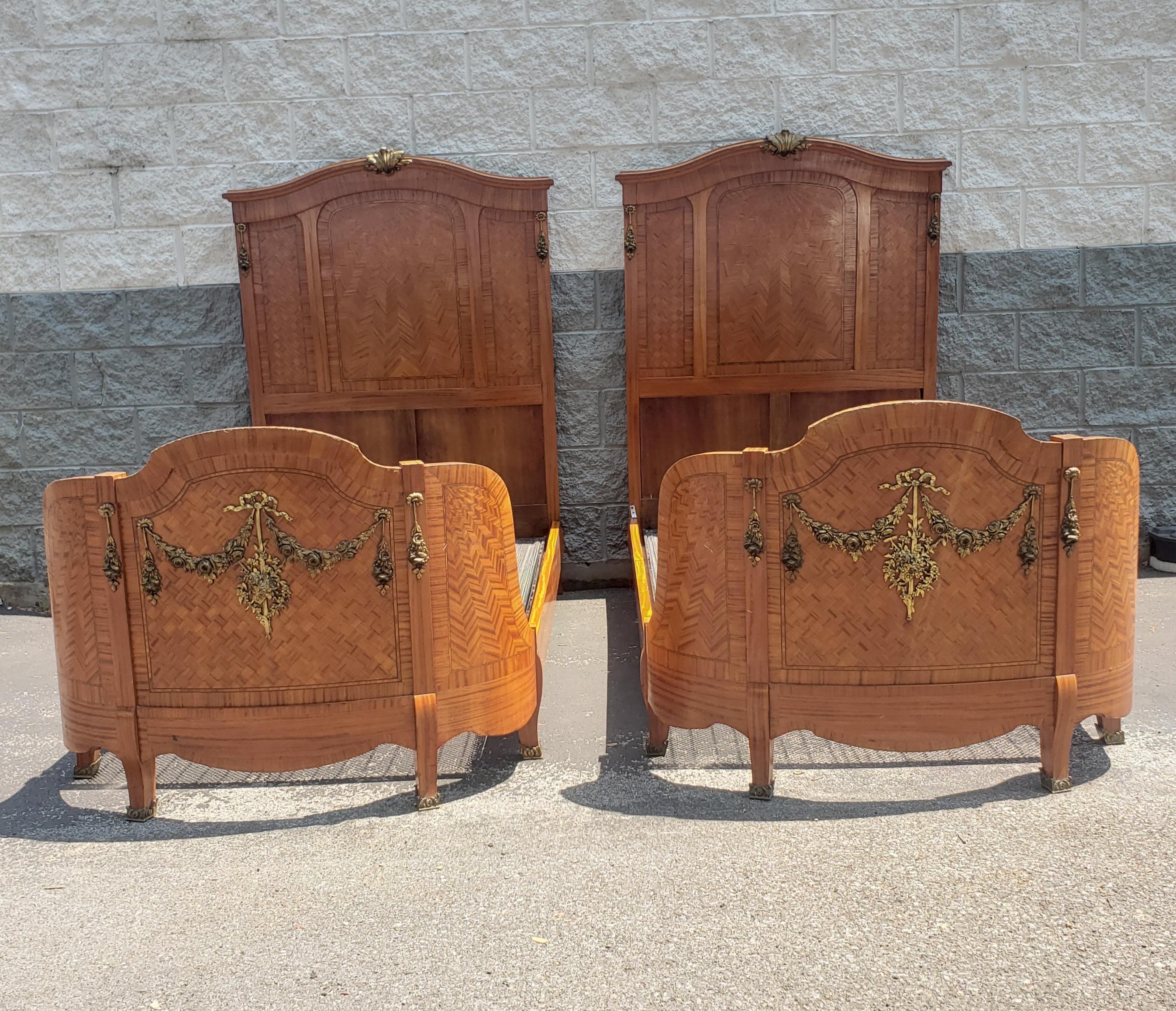 A very impressive good quality pair of late 19th century French Rococo Style parquetry and marquetry inlaid twin size bedsteads. Feautures intricate ormolu mounts on headboard and footboards. Ormolu brass caps on footboard legs. Half round footboard