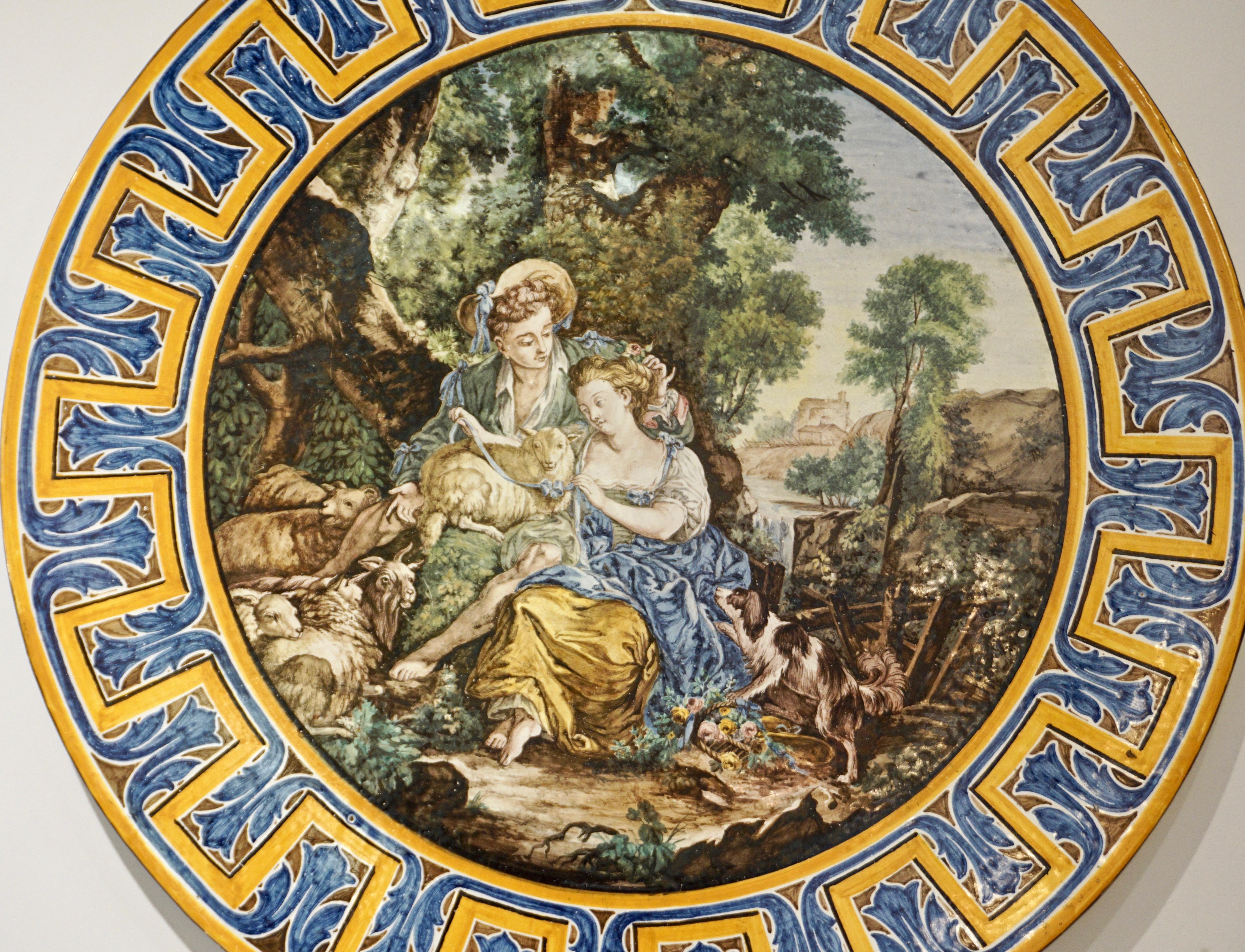 Late 19th century, very large earthenware ceramic sculpture platter or charger, of the French Second Empire period, entirely hand painted in Francois Boucher style, the romantic and subtly erotic scene as a central medallion depicts a young shepherd