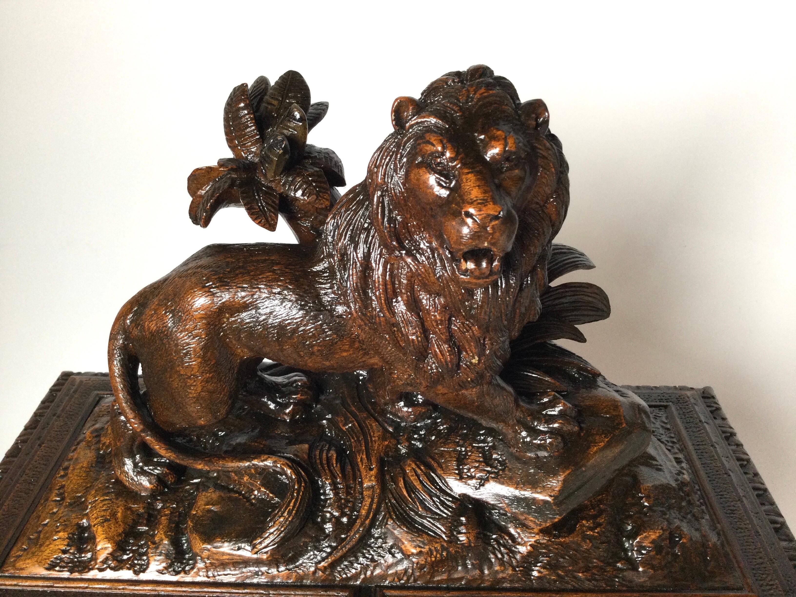 A hand carved walnut miniature cabinet humidor. The top with a majestic lion over two doors which open to reveal multiple places for cigars with two smaller drawers at the bottom. Beautifully carved in well cared for condition.