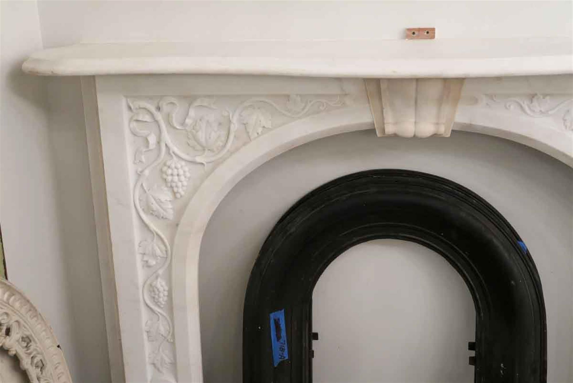 1870s pretty hand carved white marble mantel with grapevine detailing throughout the frame. This can be seen at our 2420 Broadway location on the upper west side in Manhattan.