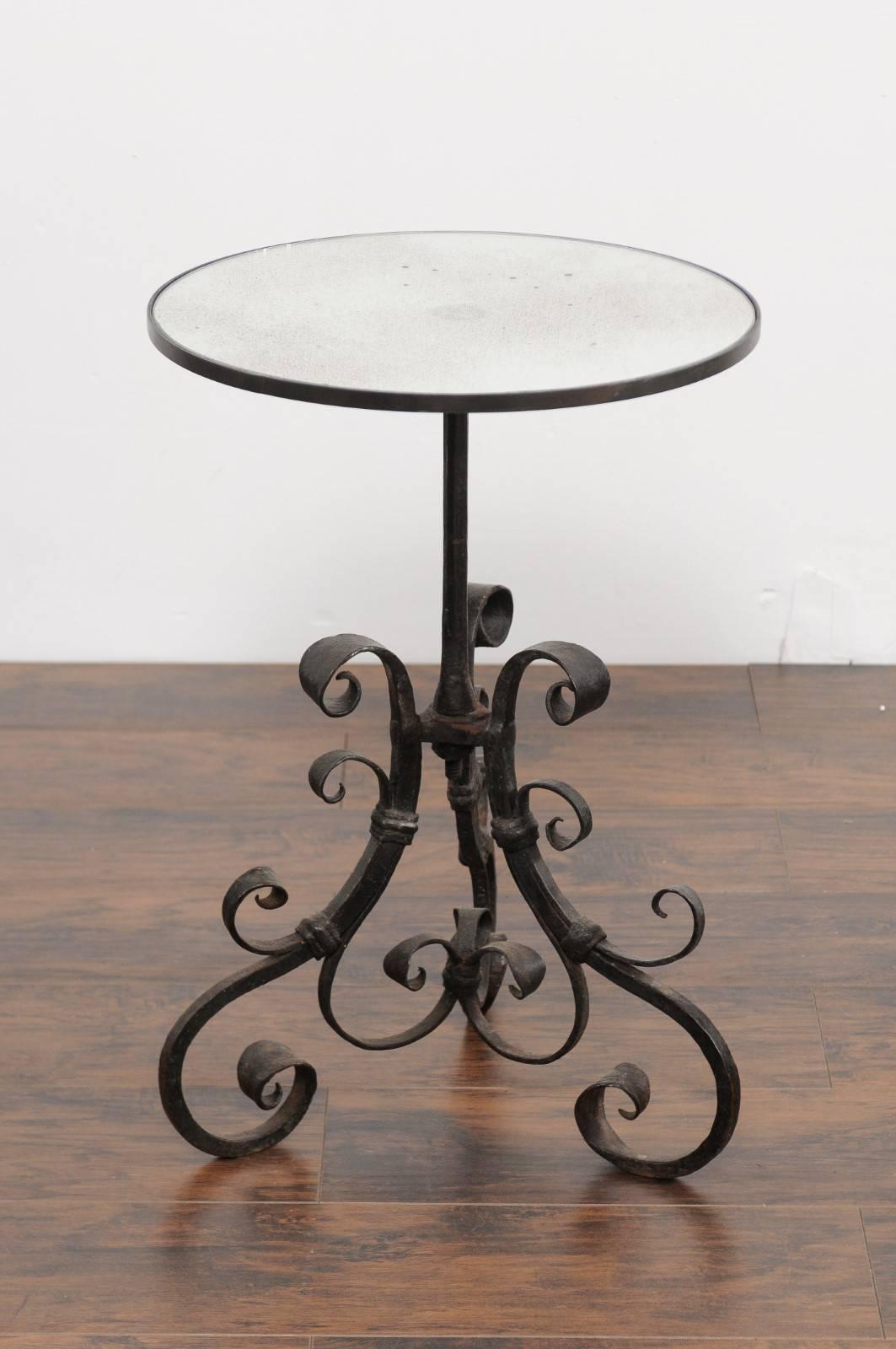 An Italian wrought iron pedestal side table from the second half of the 19th century, with new custom mirrored top and scrolled motifs. This Italian side table features a circular mirrored top with a lovely antiqued finish, supported by a 19th