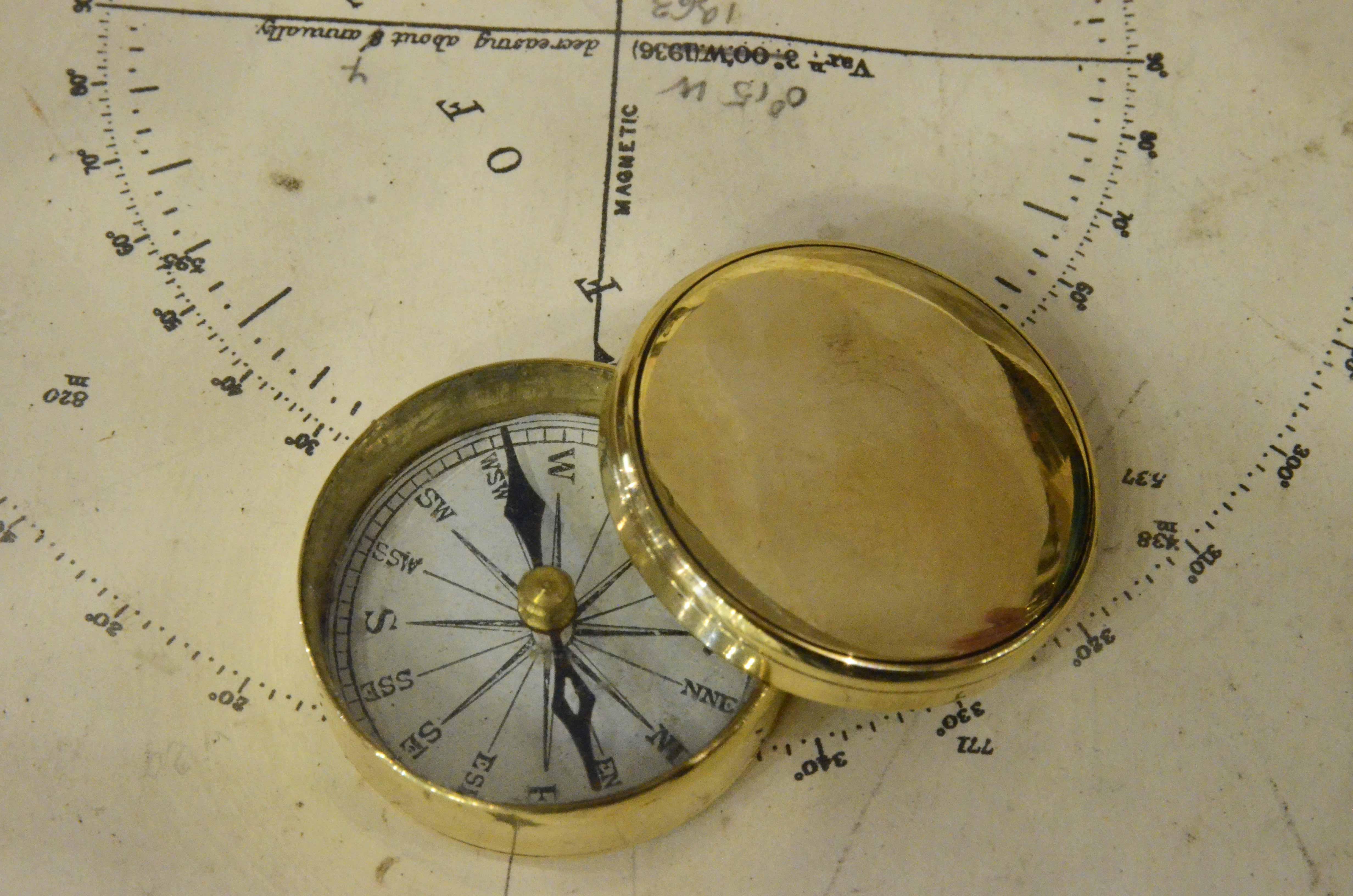 Small Magnetic travel compass, of turned brass, an instrument consisting of a magnetized needle free to rotate on a horizontal plane, marking the direction of magnetic north with the tip of the needle. 
Compass card with sixteen winds on copper