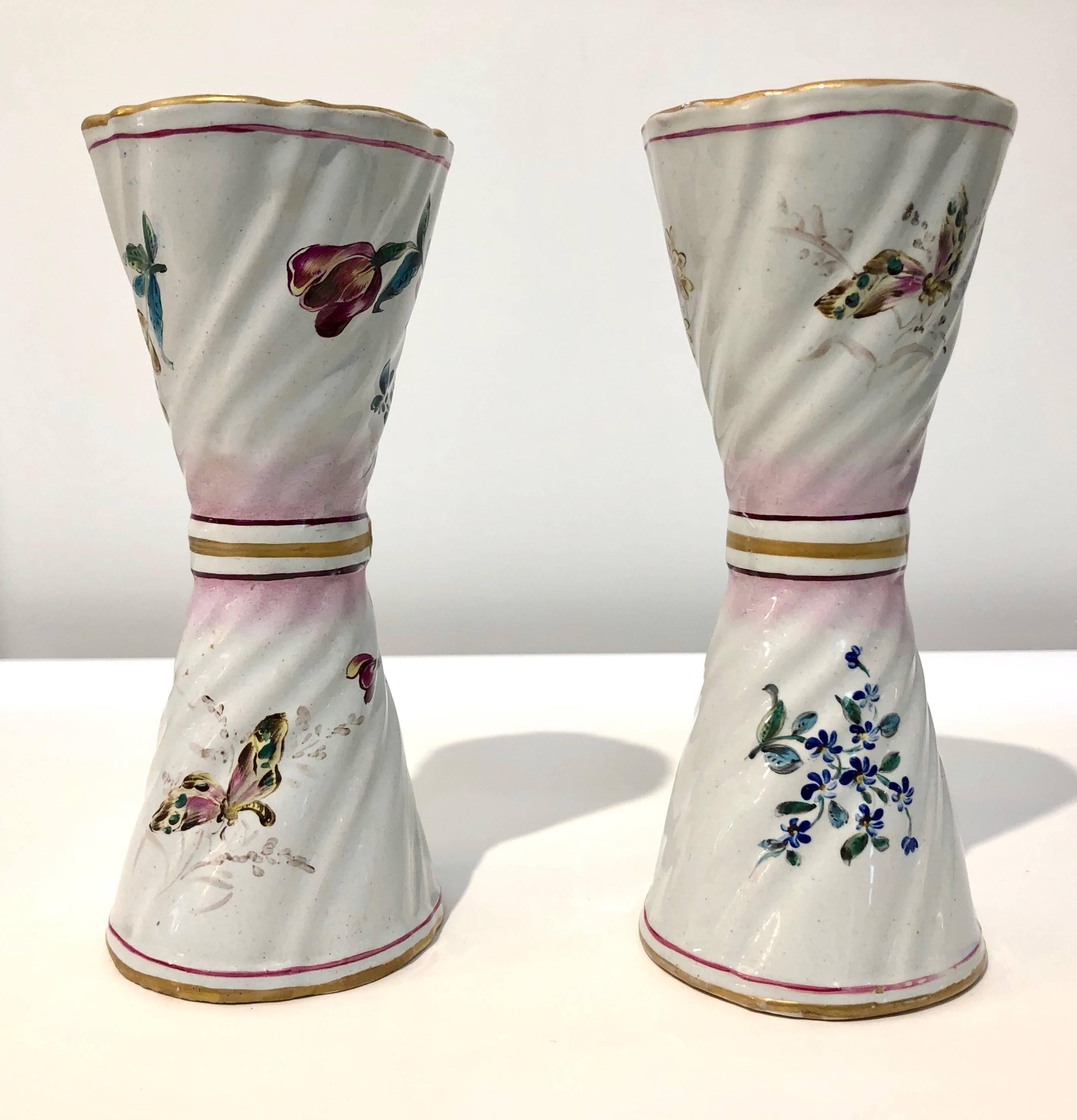 A charming pair of handcrafted flower vases, late 19th century fine French majolica, characterized by an unusual conical shape with waist, hand enameled with a gold band, decorated with finely hand-painted bunches of colored flowers distinguished by