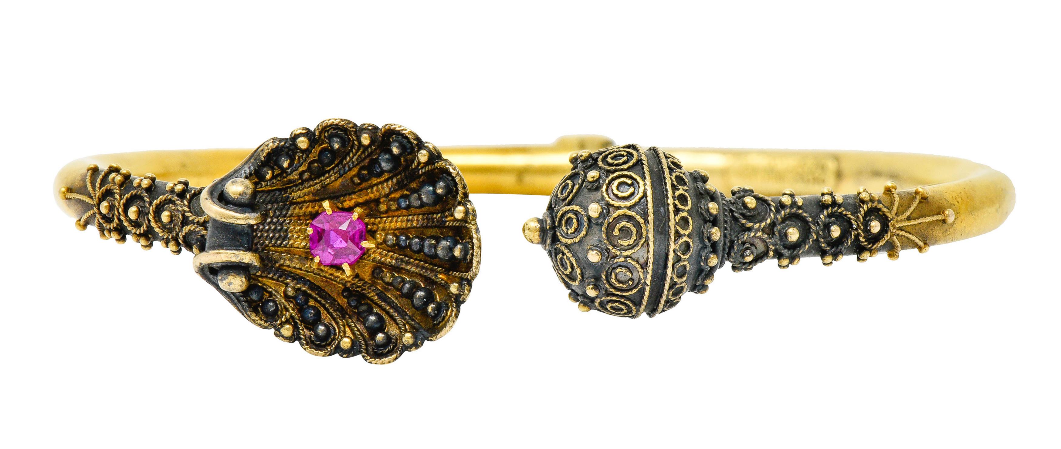 Hinged bangle bracelet terminating as a decorative ball opposite of a cupped clamshell

Both terminals are oxidized with gold beading and twisted rope details

Shell features a talon set cushion cut ruby weighing approximately 0.36 carat;