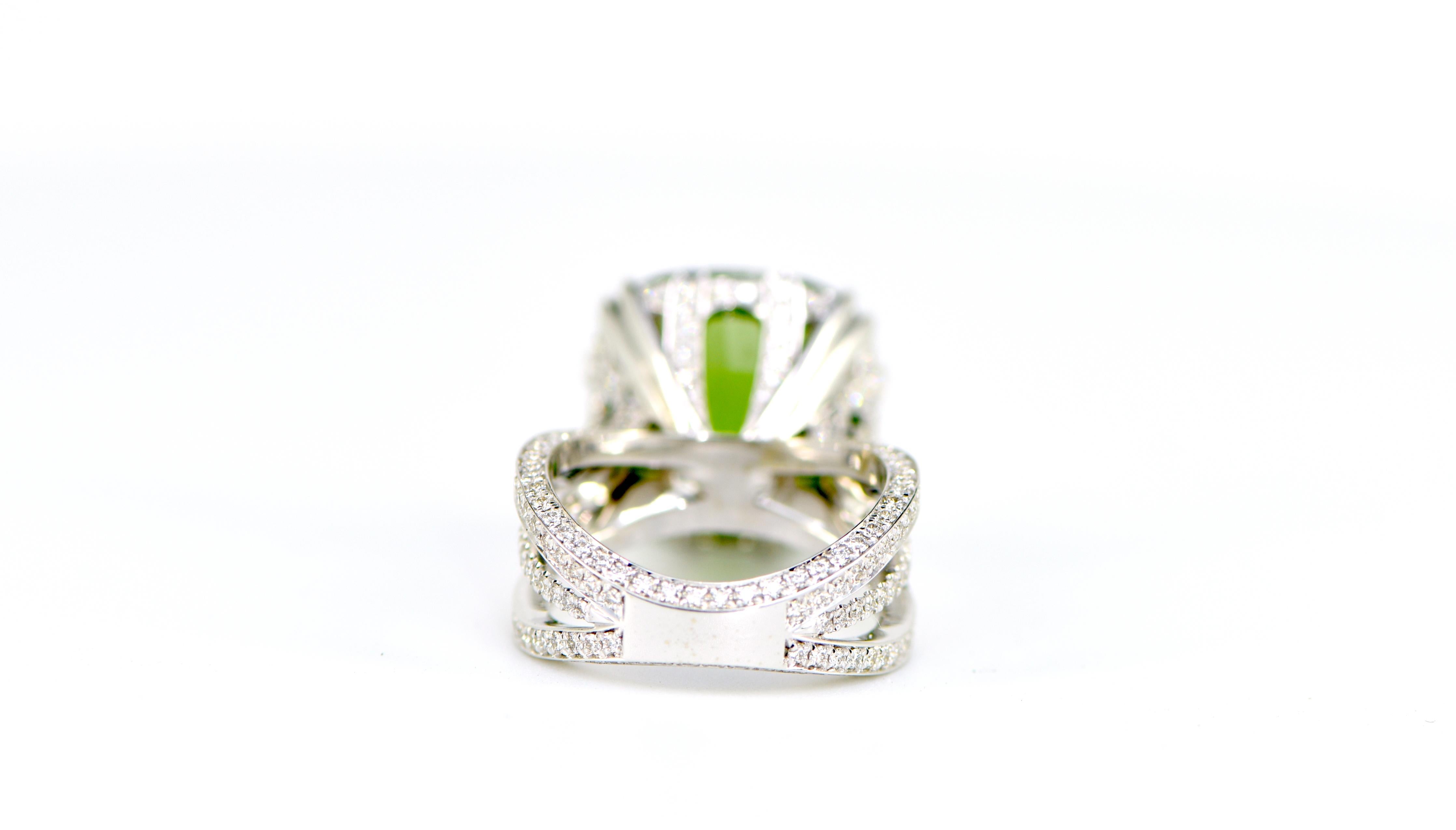  Introducing a stunning and eye-catching Burmese cushion cut peridot ring, set in luxurious 18 karat white gold. The center stone, an impressive 18.72ct peridot, radiates with a rich and vivid green color, making it the perfect statement piece for