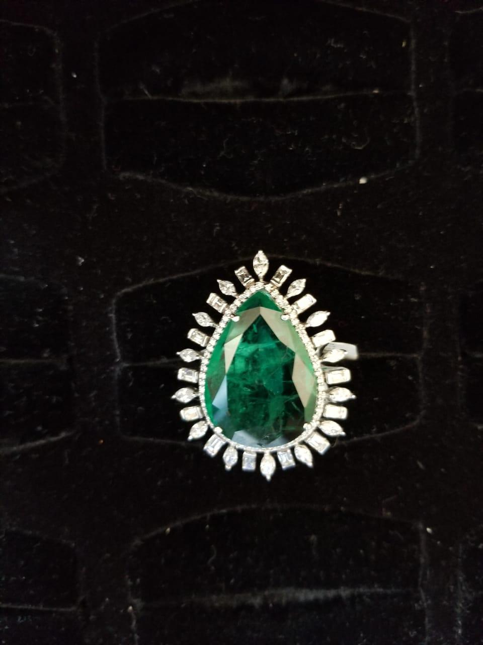 A classic Zambian Emerald and Diamond Cocktail ring set in 18K Gold. The weight of the Zambian Emerald is 18.74 carats and originates from Zambia. The Emerald is without any treatment and completely natural. The combined weight of the Marquise and