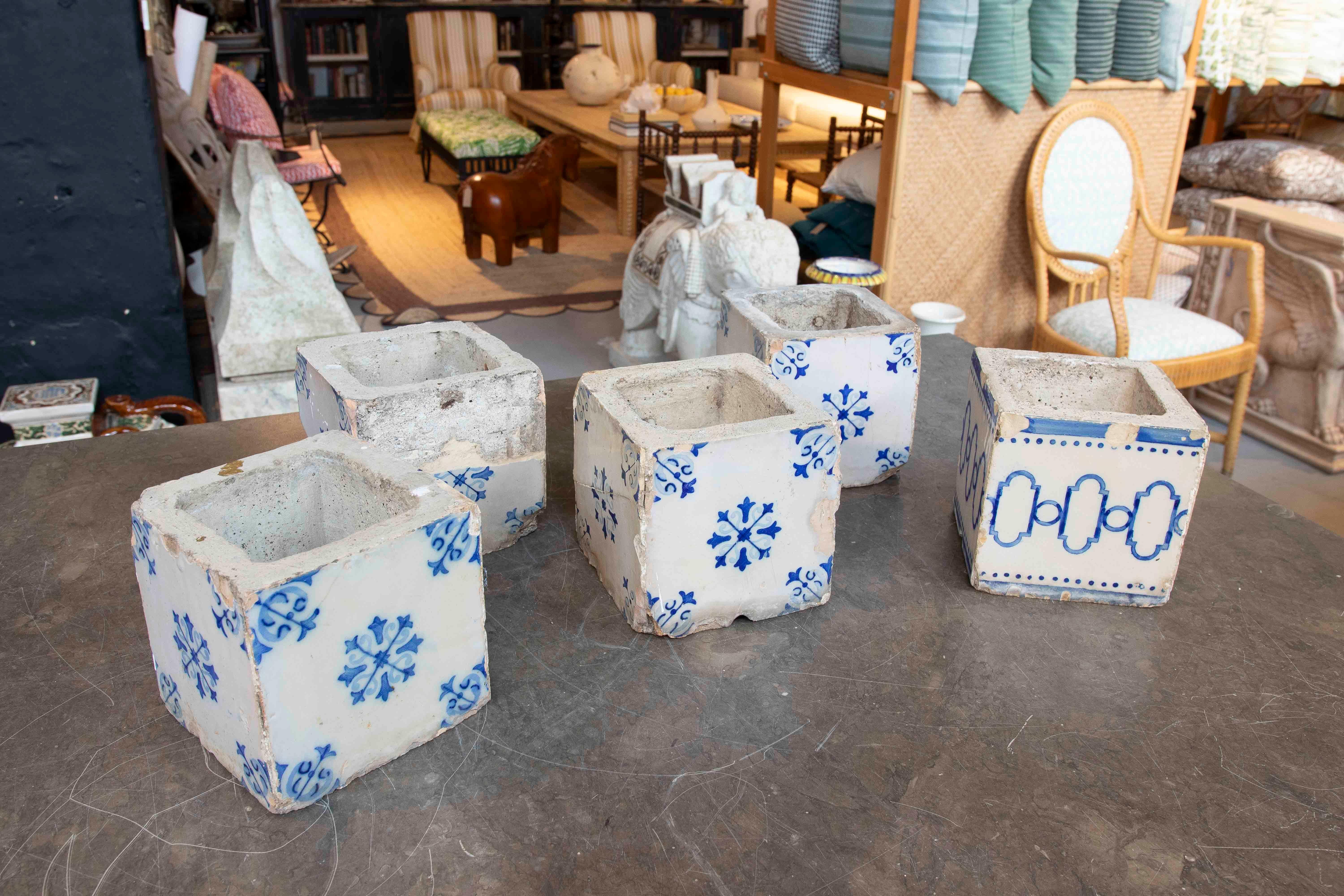 
Un set di vasi realizzati con antiche piastrelle di ceramica dipinte a mano con motivi blu e bianchi. Questi pezzi, probabilmente di origine iberica o mediterranea, presentano disegni geometrici e floreali caratteristici della tradizione