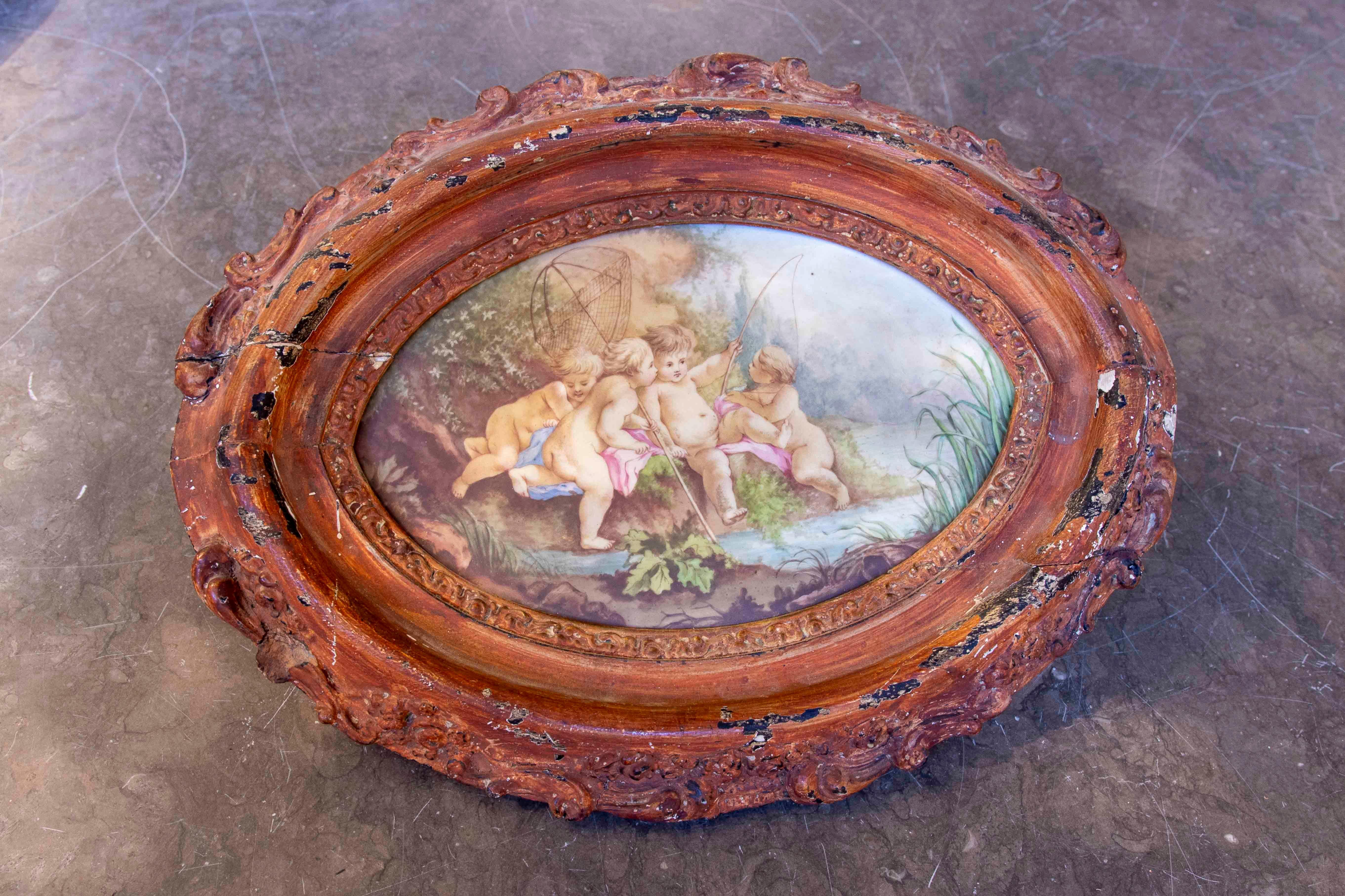 Une peinture exquise sur porcelaine de Sèvres, représentant une scène pastorale avec des chérubins dans un cadre naturel idyllique. Cette œuvre, signée par Gérard Derickweiler, est encadrée dans un cadre ovale en bois sculpté, au dessin orné et à