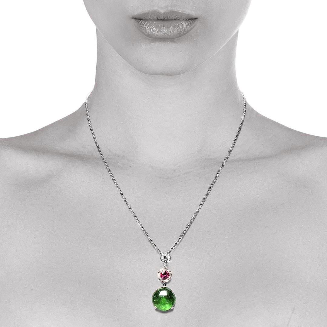This diamond set enhancer showcases a beautiful round green tourmaline cabochon. Its gorgeous colour is offset by a very lively round pink tourmaline or rubellite, surrounded by small grain set round diamonds. This is a detachable pendant with a