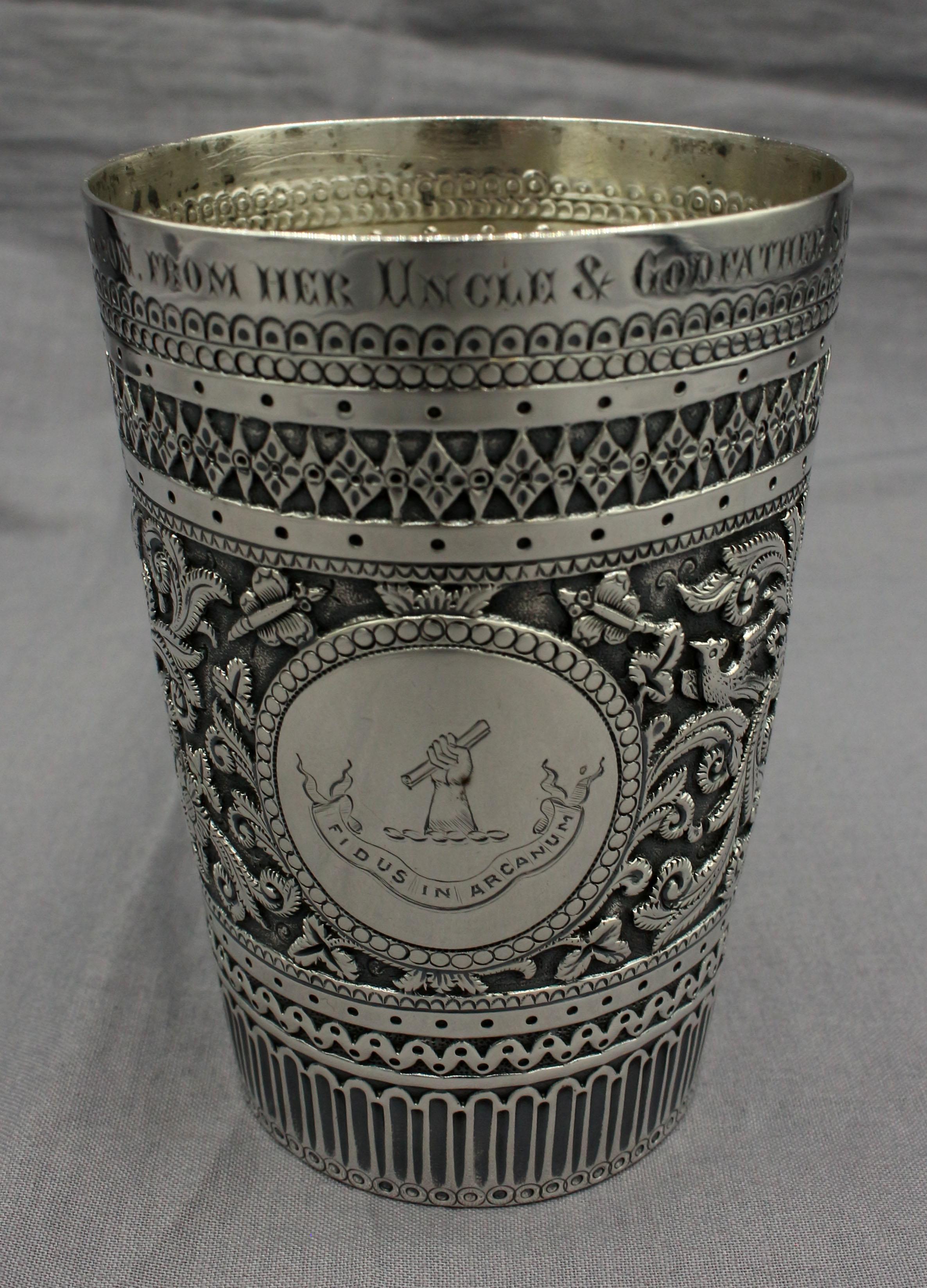 1878 sterling silver beaker, London, made by Henry Holland. Presentation inscription: Annette Orme Stevenson from her Uncle & Godfather S.H. Fourdrinier. In the exotic hand chased style of the Aesthetic Movement. Motto: Fidus in Arcanum (Faithful in