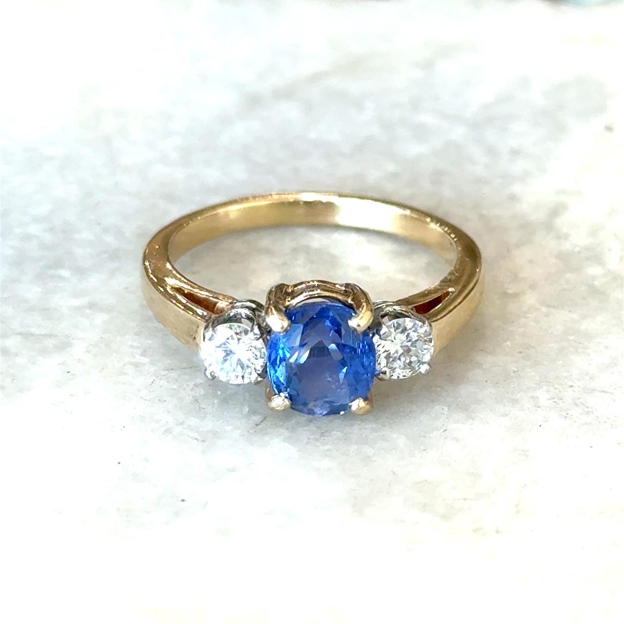 Cette bague vintage à trois pierres date des années 1950 et comporte un saphir bleu ovale de Birmanie de 1,51 carat naturel non traité, avec un rapport de laboratoire GIA.
Il est flanqué de deux diamants ronds.
Couleur F  VS-SI Clarity .36CT poids