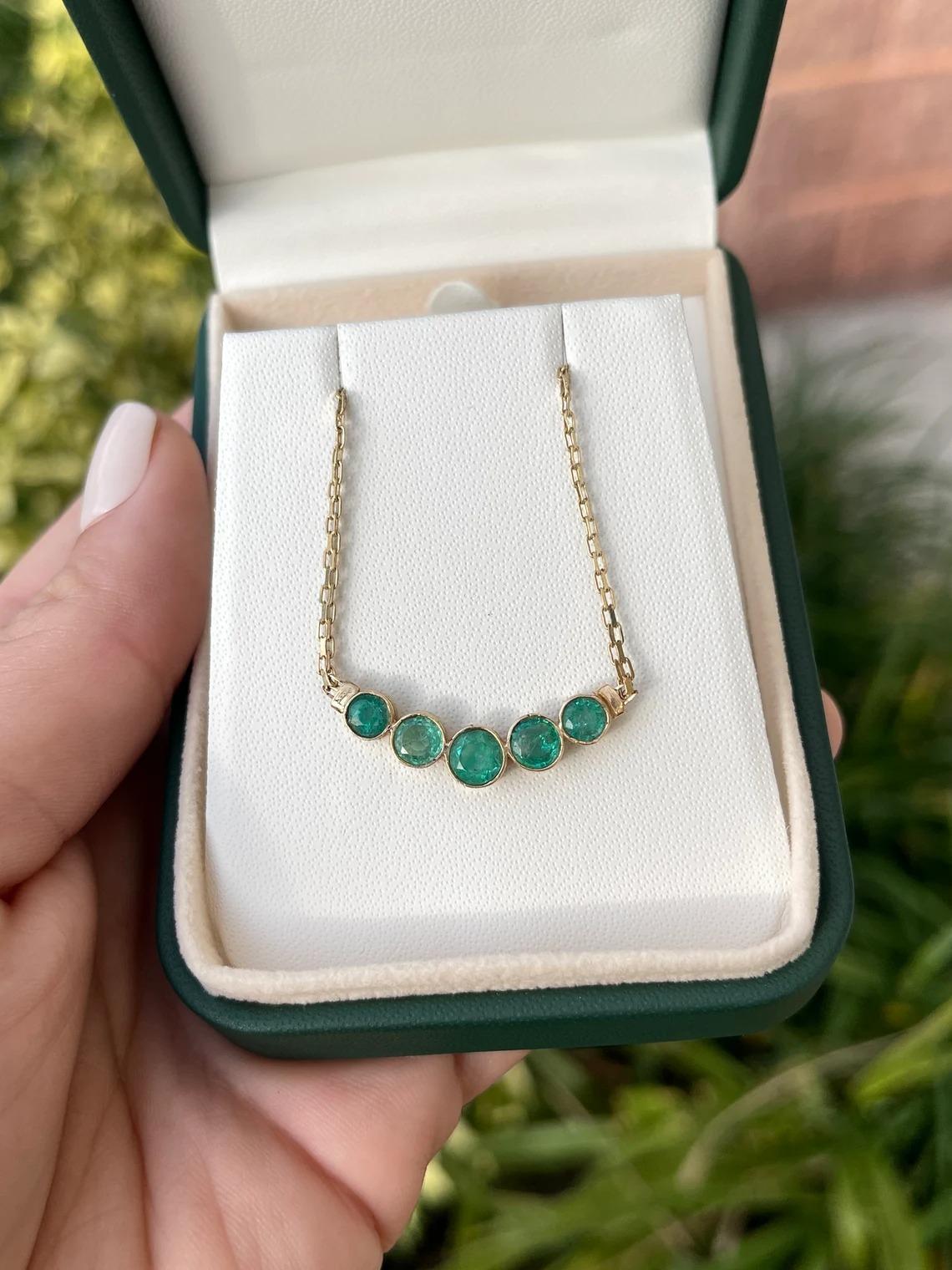 A five-stone emerald everyday necklace. Handcrafted in solid 14k yellow gold, the piece showcases natural emeralds individually bezel set. Each stone is completely natural and genuine. The chain measures 17 inches long and lays perfectly around the
