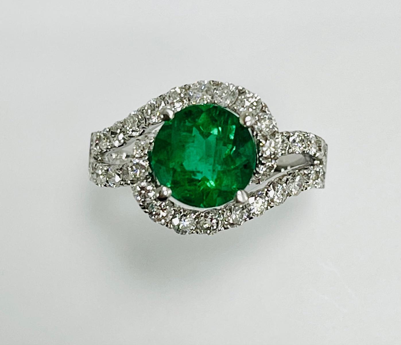 1.88 Carat zambian round shape emerald set in 18k whit gold ring with 1.21 carat diamonds around it and half way on the split shank .