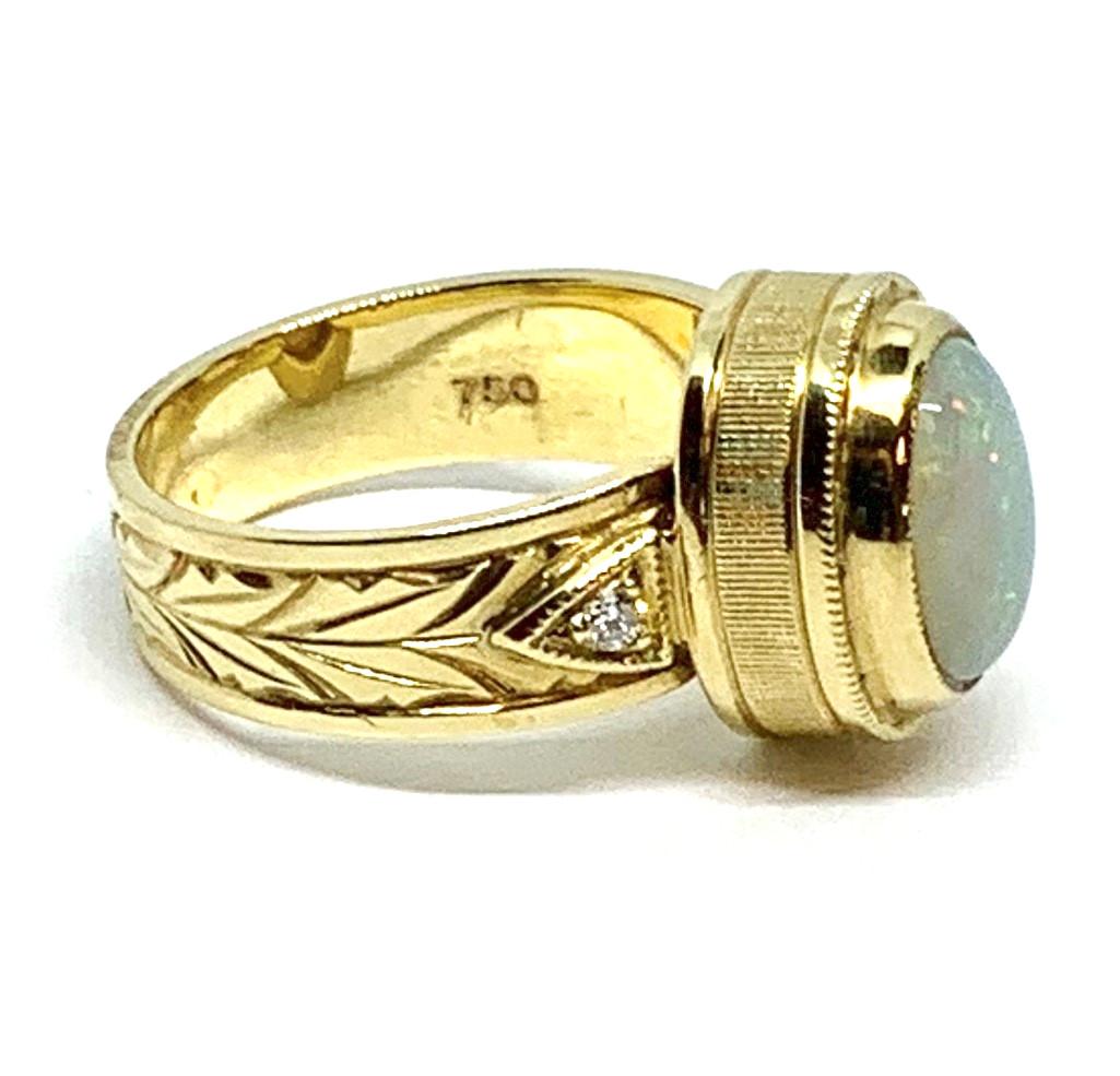 Dieser handgefertigte Ring aus 18 Karat Gelbgold ist mit einem hübschen Opal-Cabochon verziert! Der Opal ist durchscheinend mit einer silbrig-grauen Körperfarbe, die den perfekten Hintergrund für das Farbenspiel des Opals, auch bekannt als 