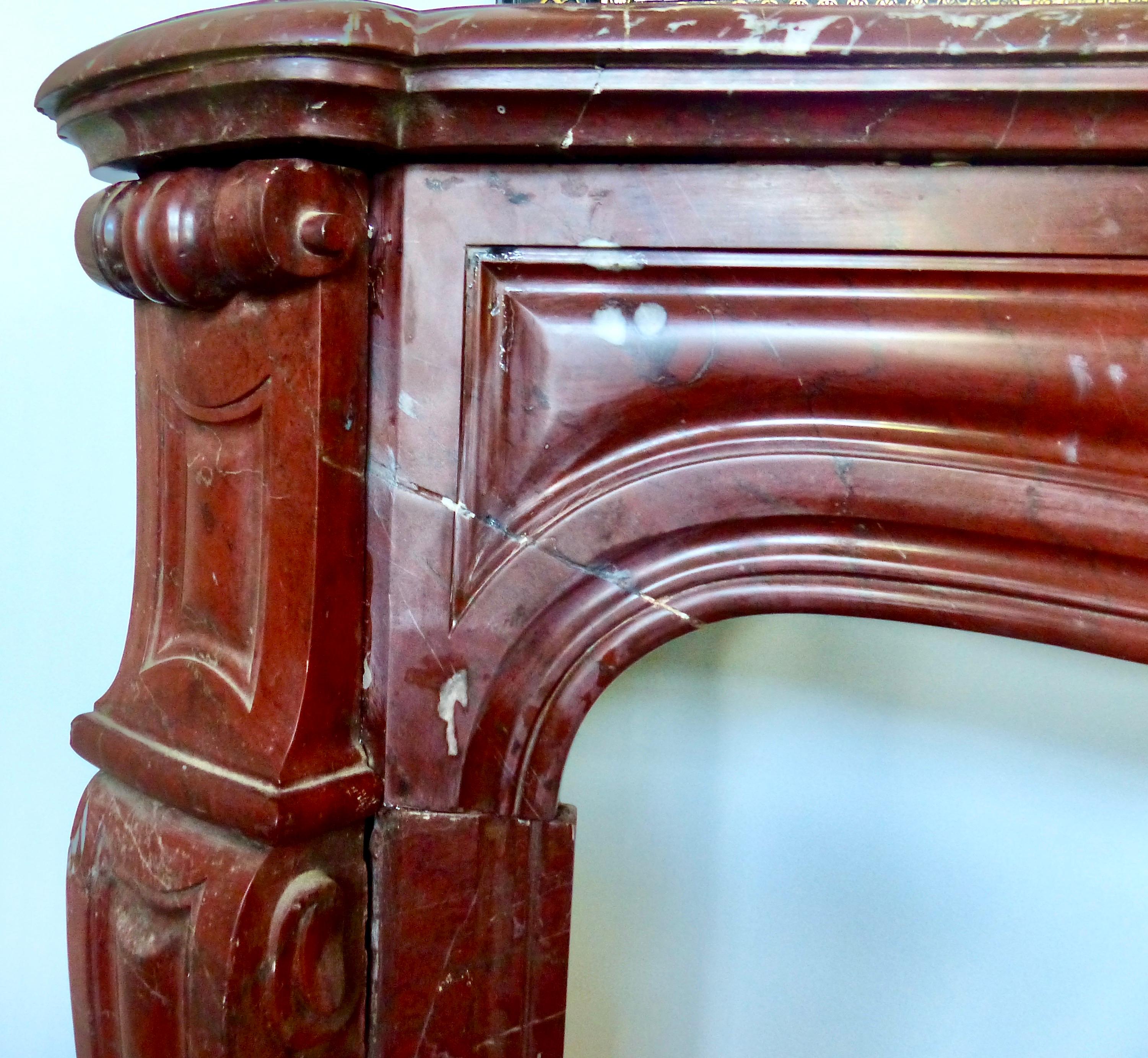 A French handcrafted, circa 1880-1890 fireplace surround in ‘Rouge de Rance’, a rare red marble with subtle white or grey veining. This Classic style and sized fireplace surround features beautiful hand carved scrolls. An investment piece that you