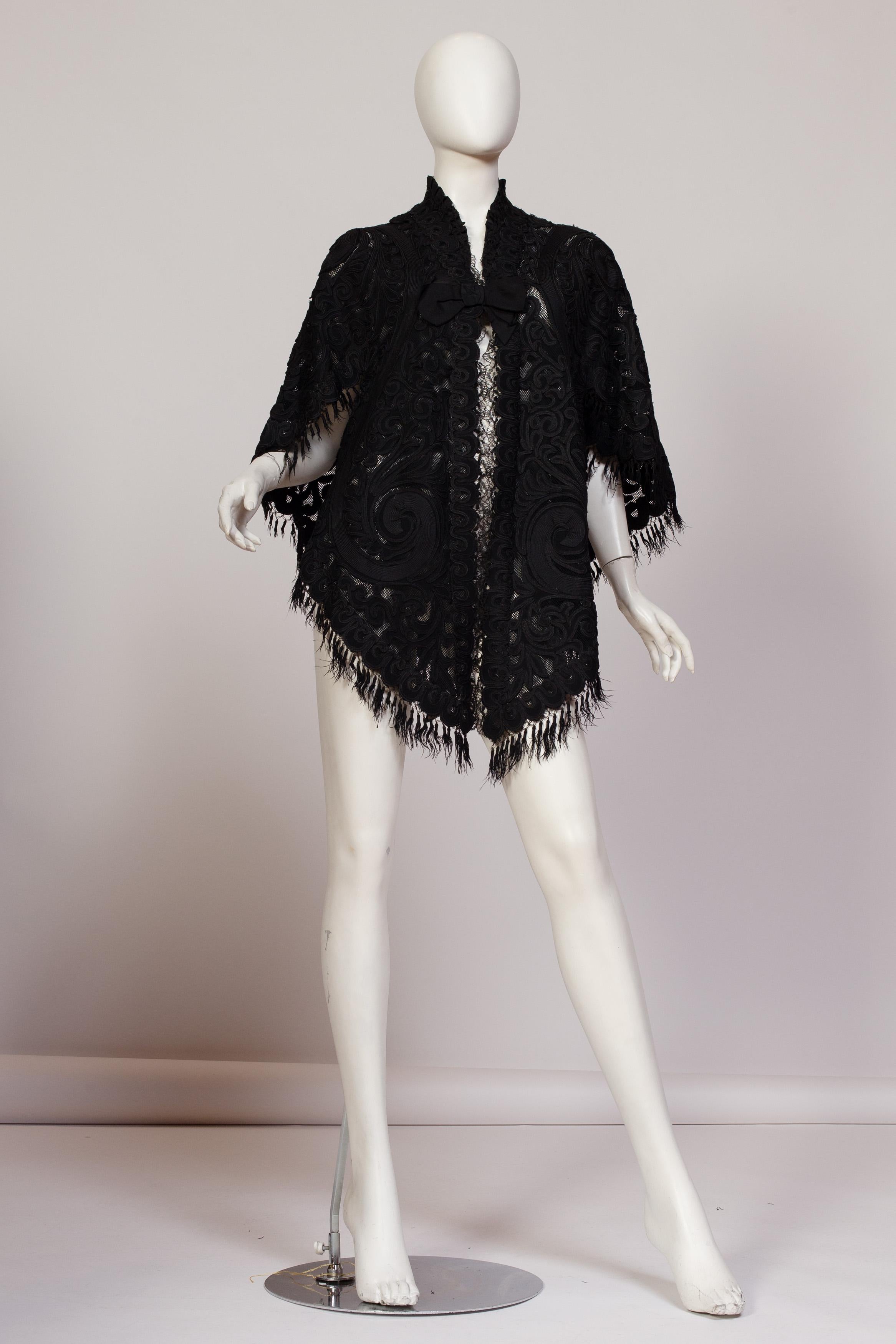 The sturdy net is covered in baroque wool appliqués outlined with silk soutache braid. The neckline and center front are edged in handmade cluny lace. The hem is trimmed in silk tasseled fringe which is the only area really showing age. In pretty