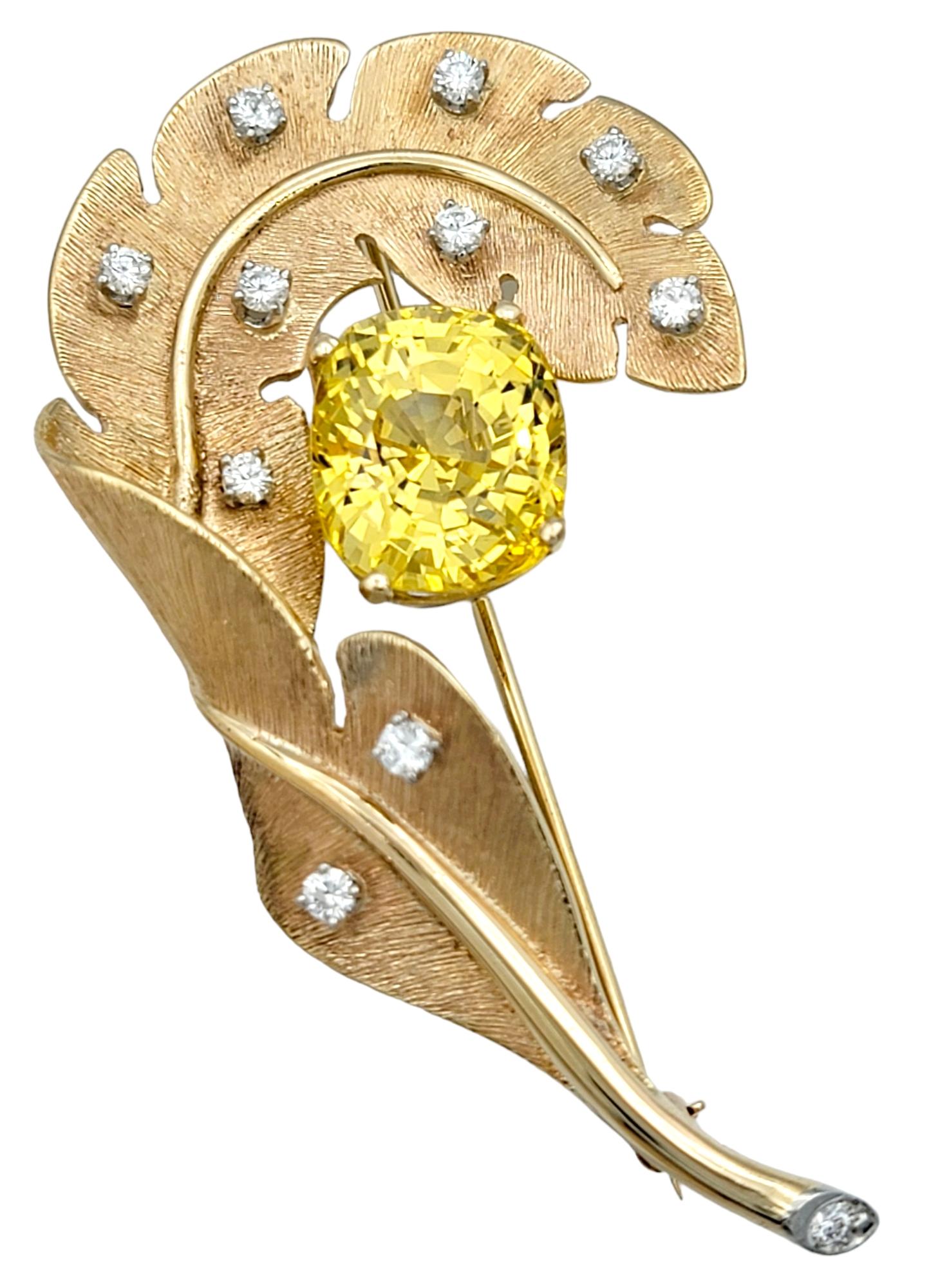 Introducing this breathtaking yellow sapphire & diamond feather brooch, crafted in 14 karat rose gold. This unique brooch features a stunning 18.80 carat vibrant yellow cushion cut sapphire at its center, exuding a golden yellow hue and exceptional