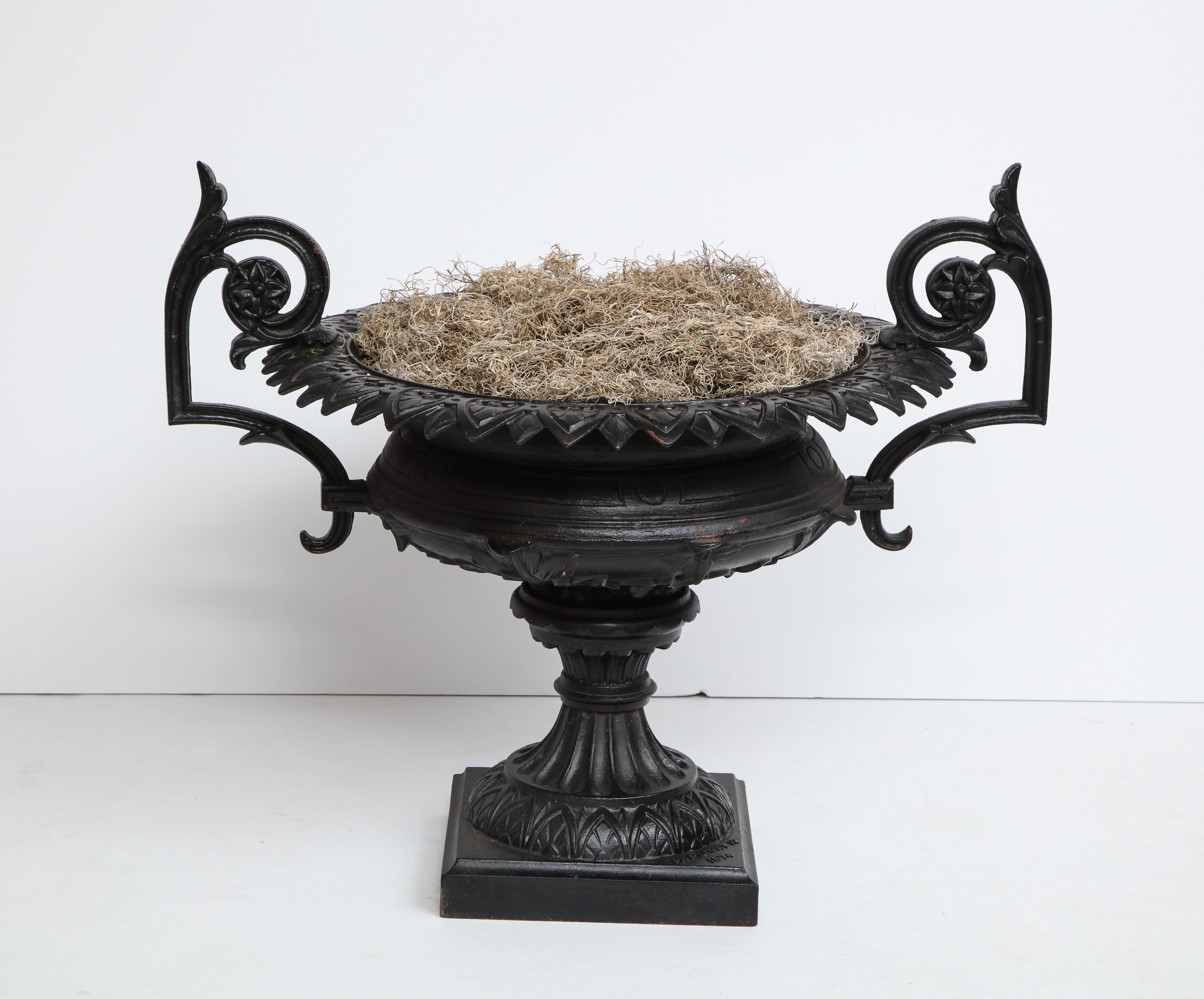 1880 Fiske cast iron twin handled urn having incised bowl over socle and stepped base.