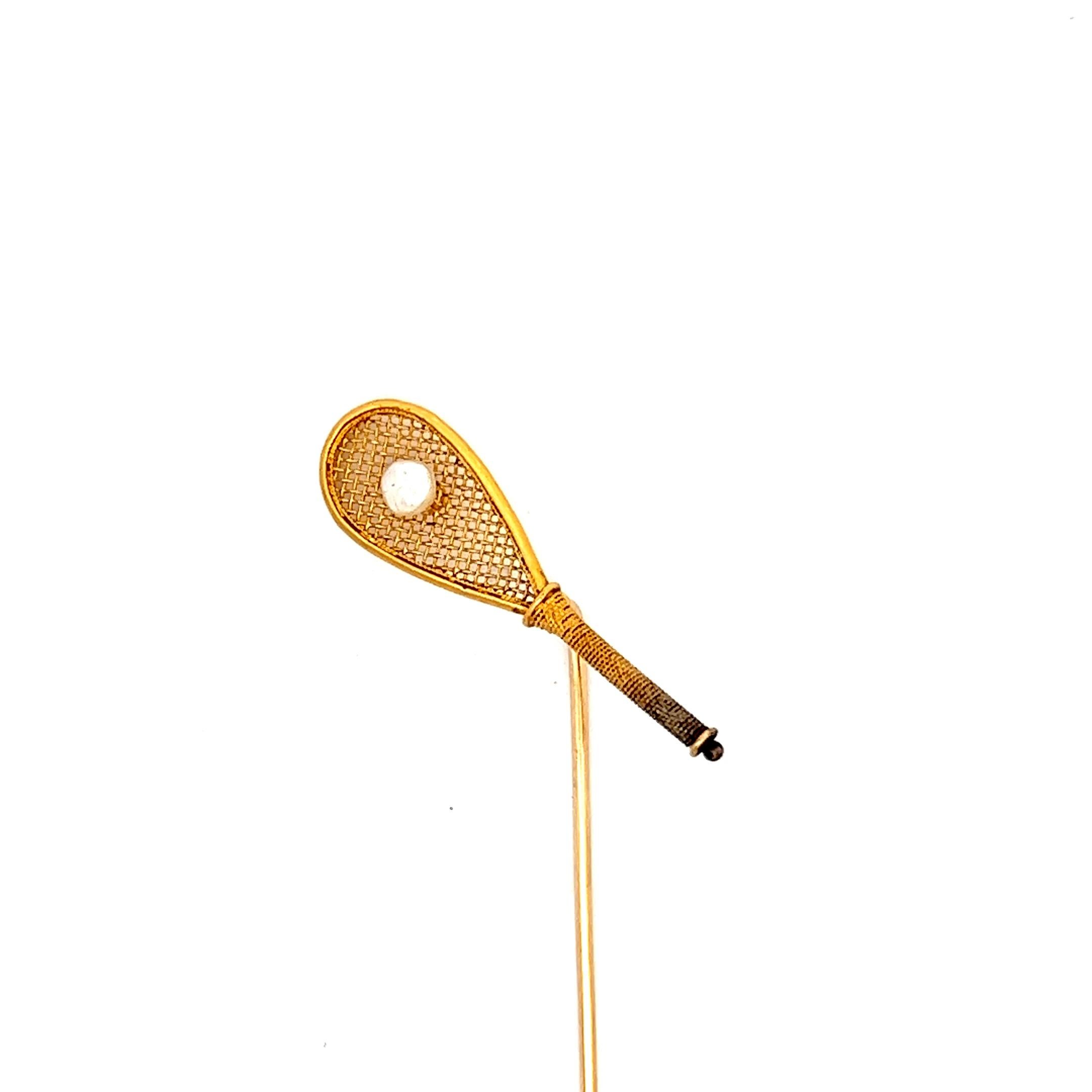 

This lovely little stick pin from the early Victorian Era features a real tennis racket in 18K yellow gold with a pearl as the cork ball in the center. The detail in this pin is incredible, from the woven mesh to the wrapped grip tape on the