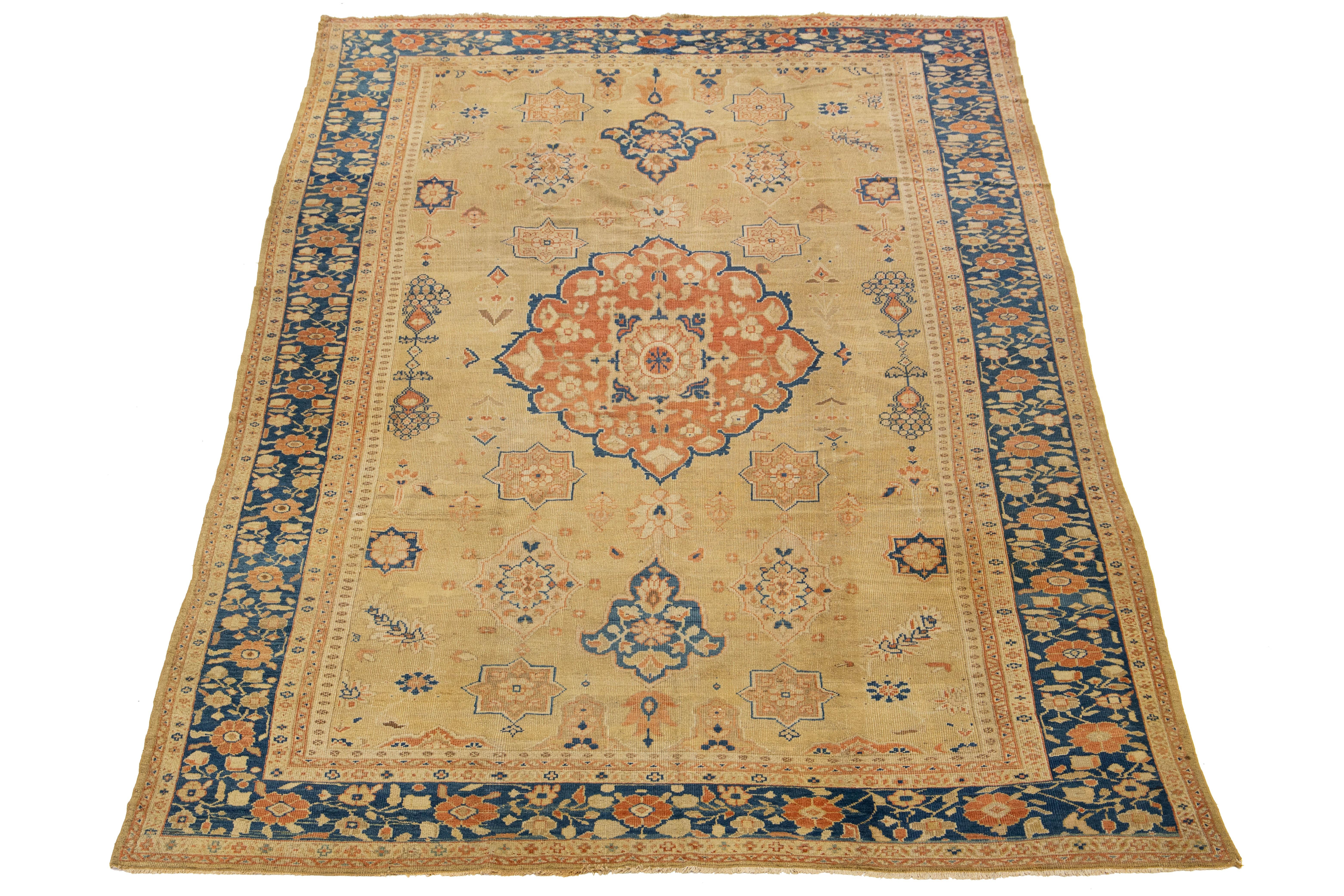 Ce tapis exquis se compose d'une base beige-tan, le cadre bleu étant magnifiquement orné de motifs floraux rouille complexes qui témoignent de l'art et de l'artisanat des motifs traditionnels de Sultanabad. C'est un choix idéal pour ajouter de la