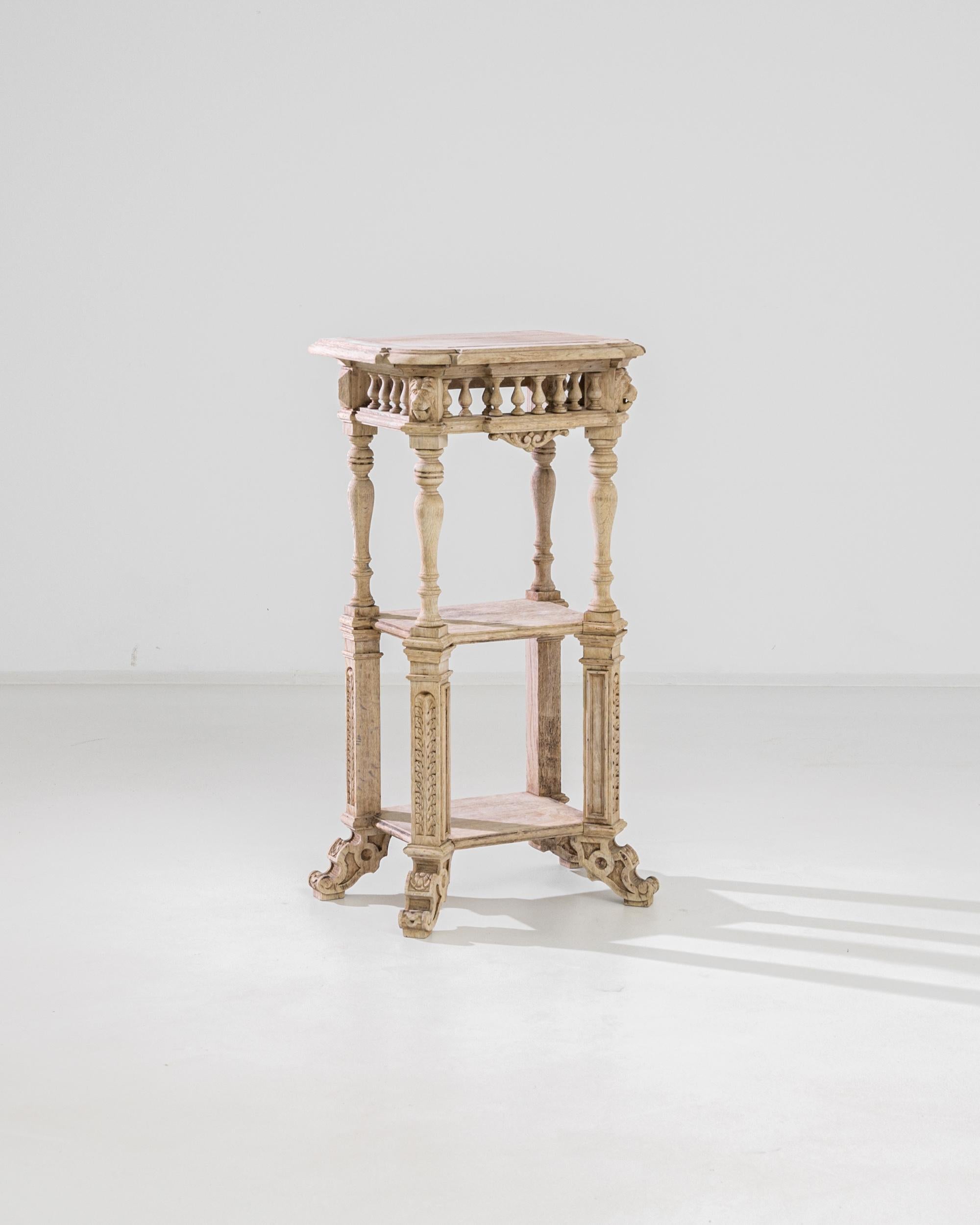 A bleached oak console table from Belgium, produced circa 1880. An ornate antique console table standing three feet tall on four style changing, two-tier legs supported by ornately carved feet featuring prominent flower motifs. Crowning the legs are