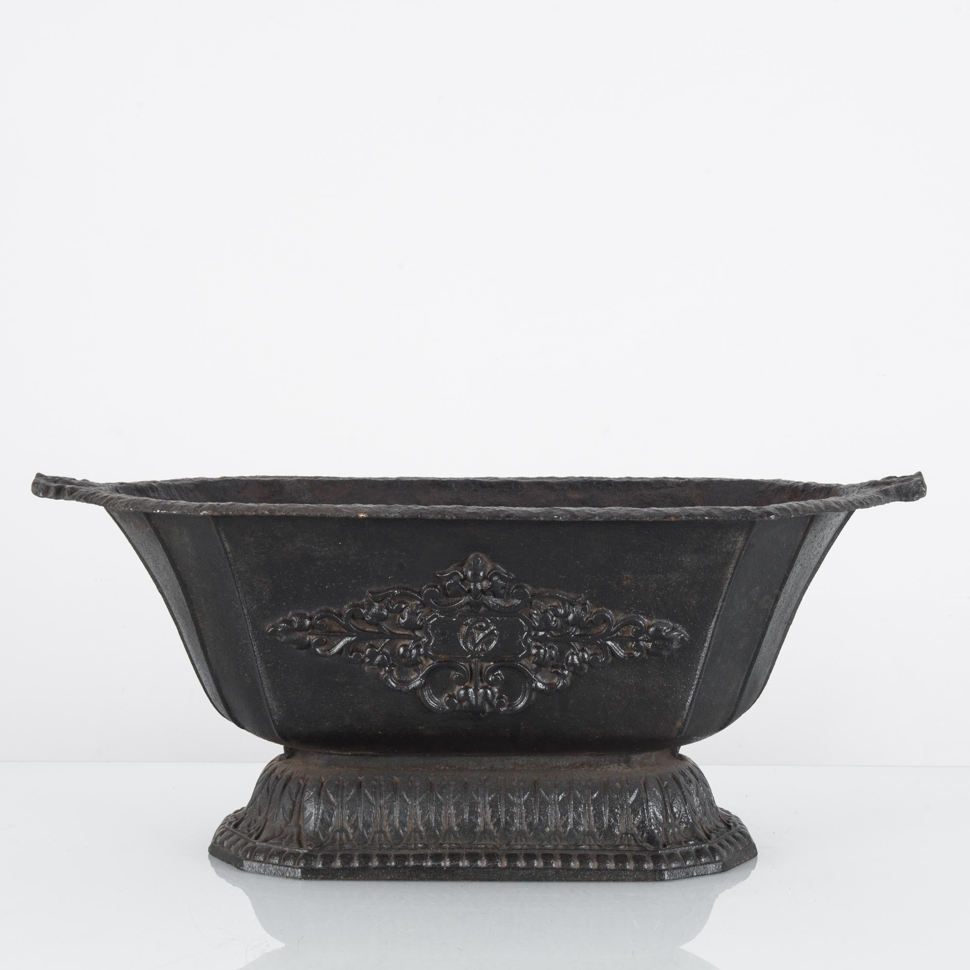 An antique cast iron planter from Belgium, circa 1881. A hearty planter in a classic, practical design ready for interior or exterior use. Marked on the side by a floral crest in relief hovering in stasis above etchings around the lower rim,