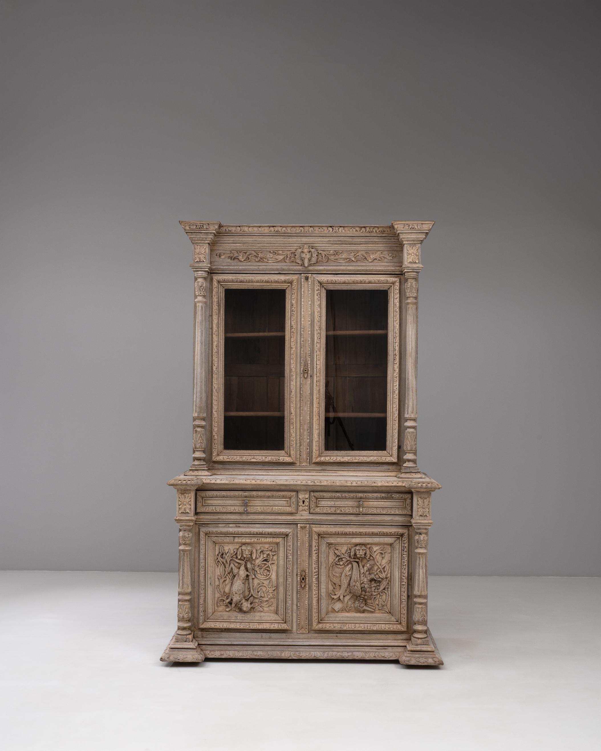 Cette vitrine belge des années 1880 témoigne d'un savoir-faire exquis et de détails complexes caractéristiques du design européen de la fin du XIXe siècle. Construite en chêne massif, la pièce présente des panneaux profondément sculptés avec